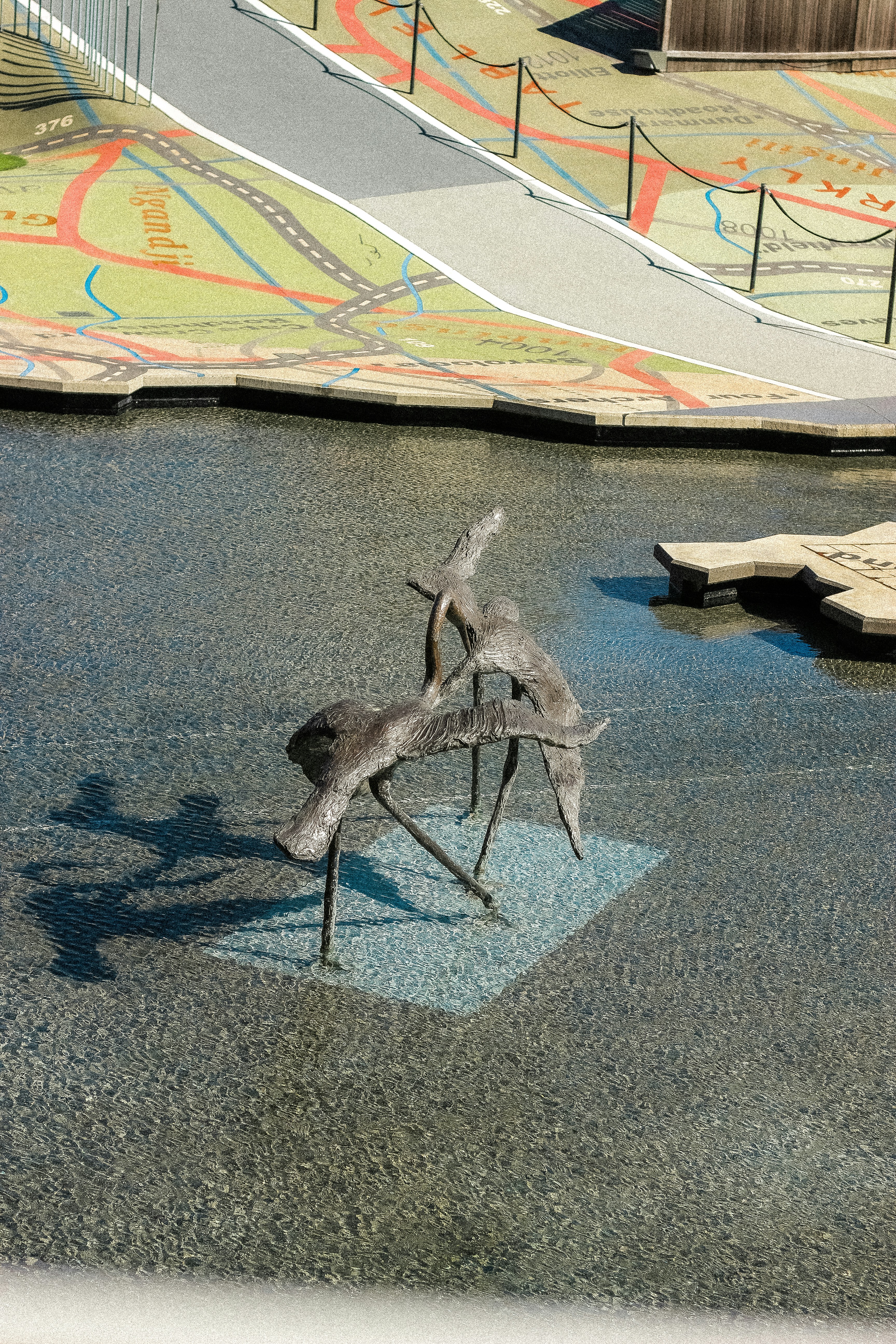 Bronze deer sculpture in shallow water with map background