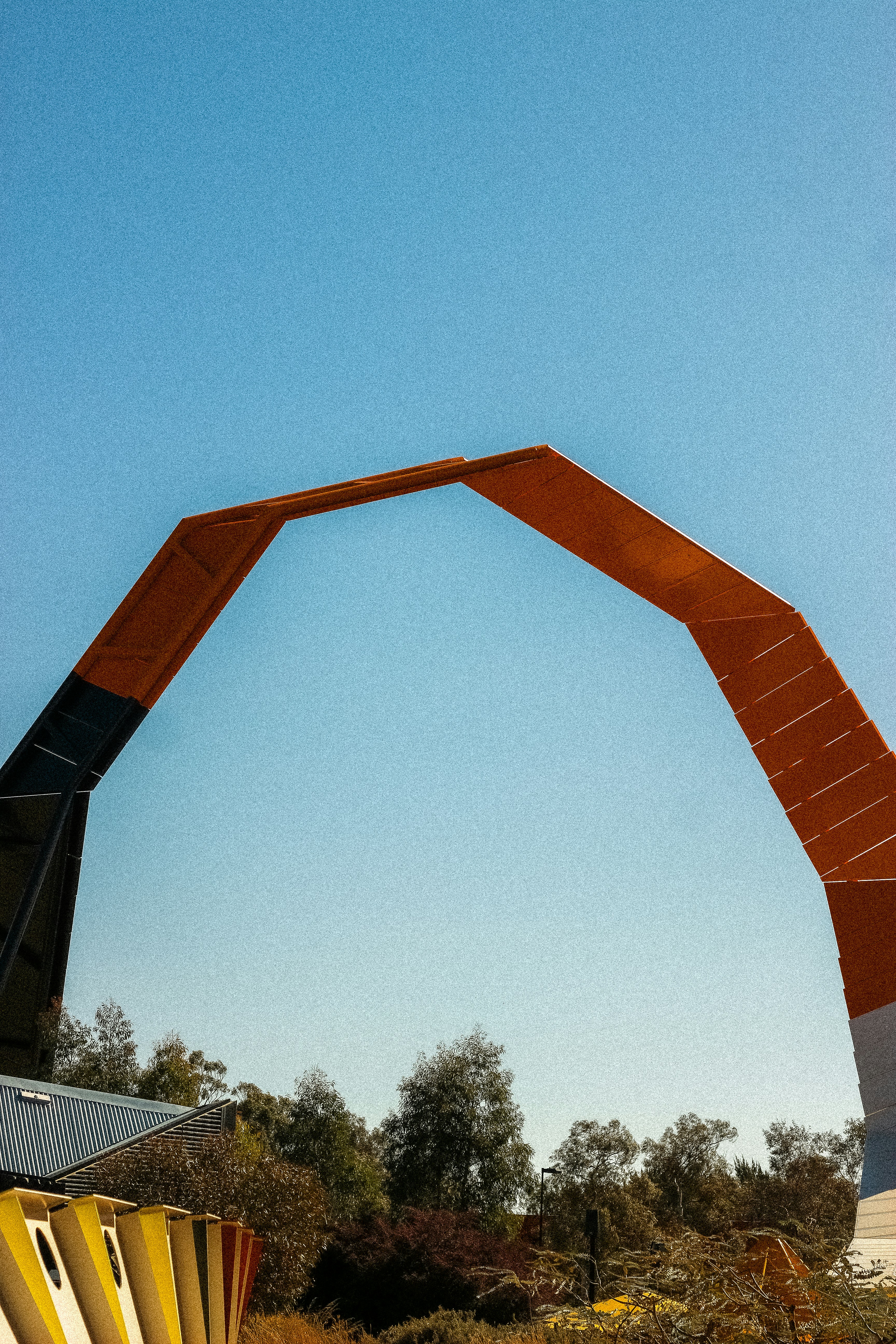 Arco naranja moderno contra un cielo azul claro