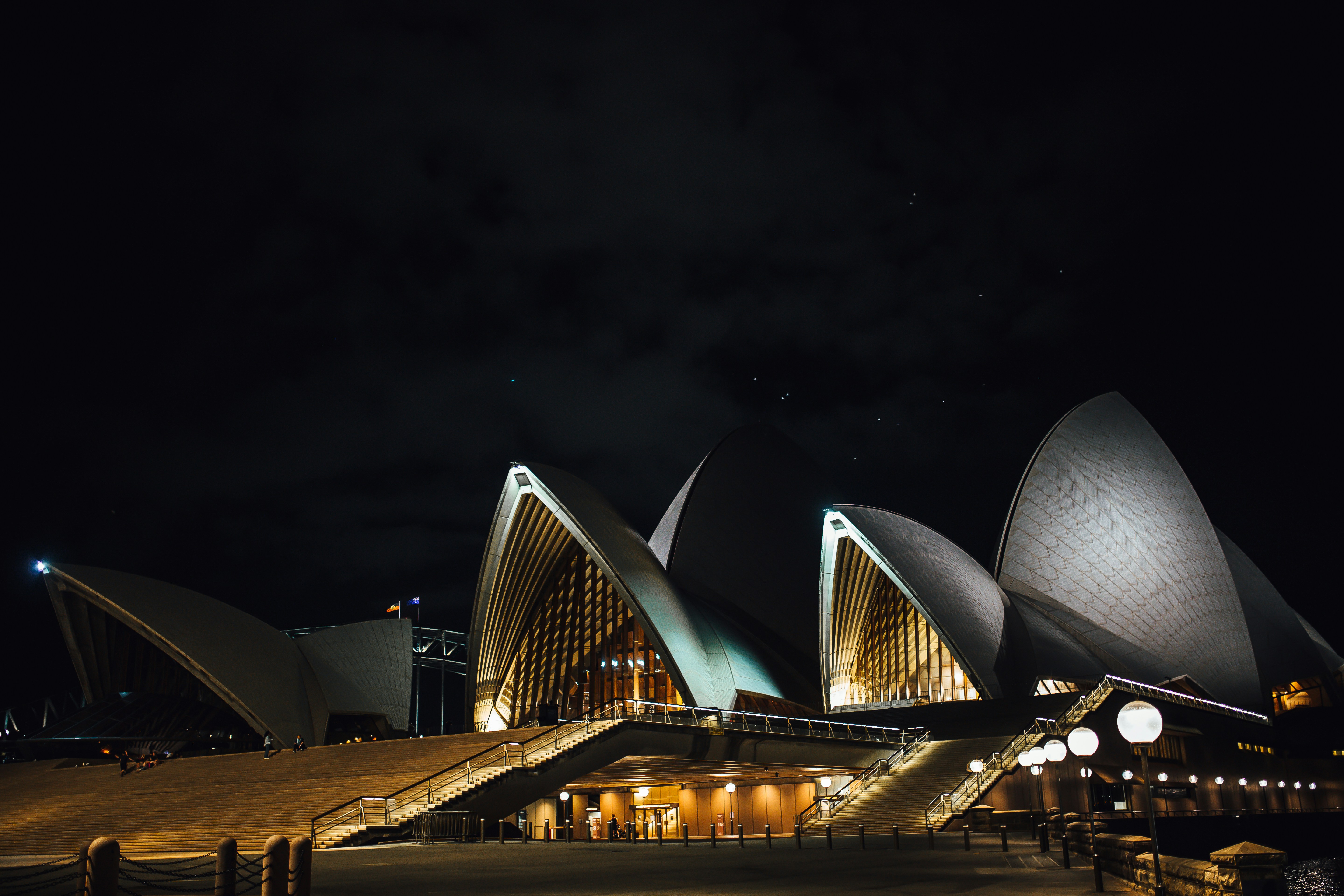 Ópera de Sídney iluminada de noche bajo un cielo estrellado