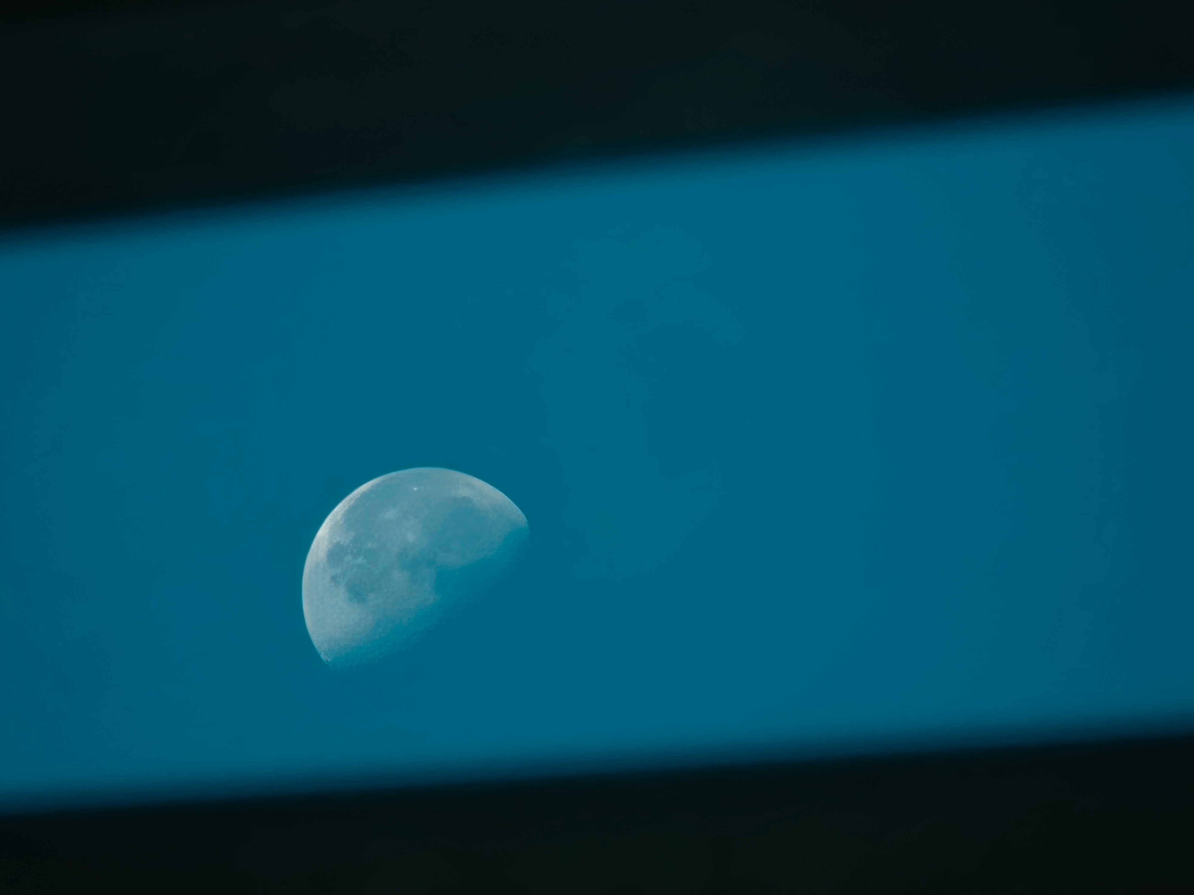 Half moon visible through a blue frame.