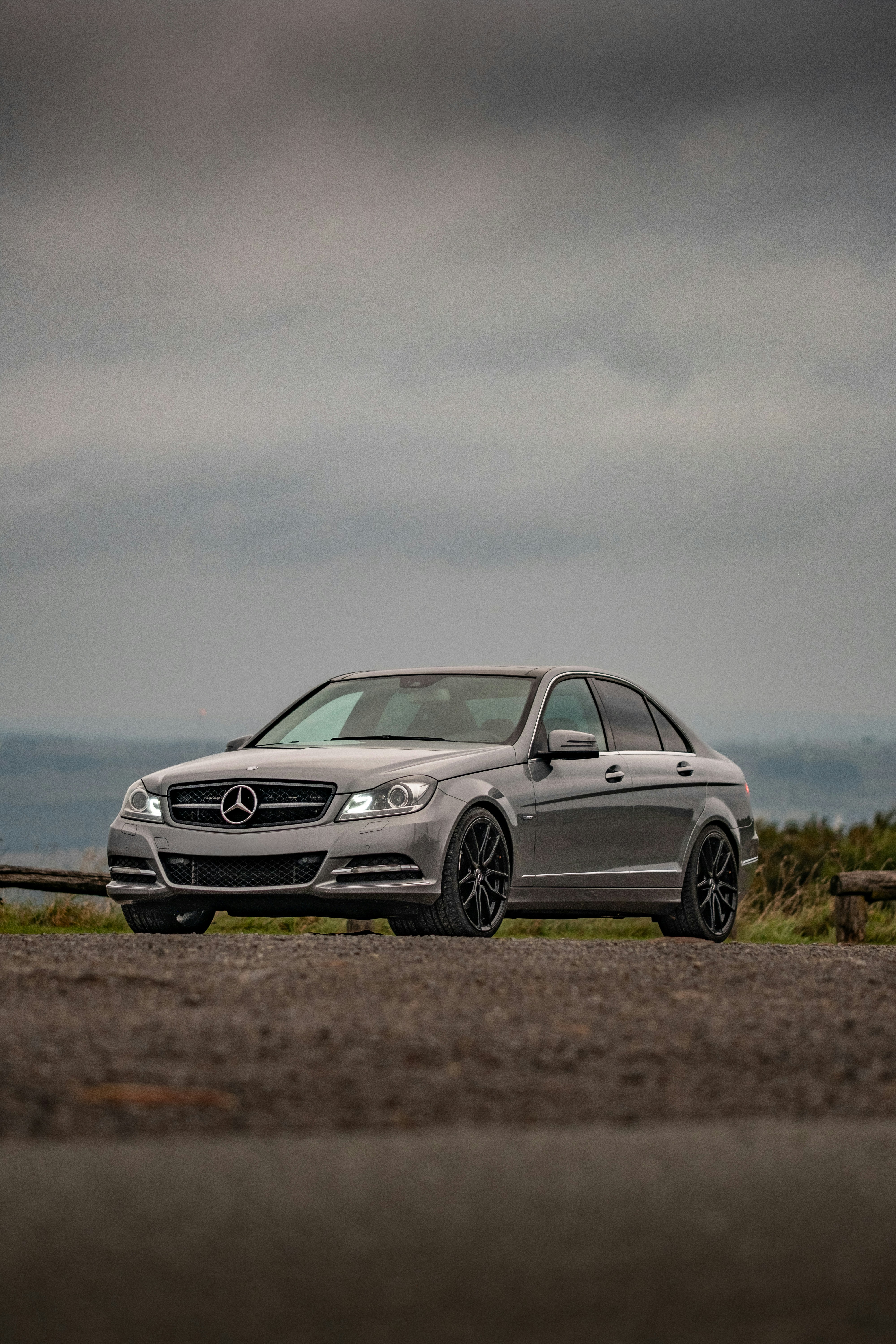 A grey sedan parked on a gravel road