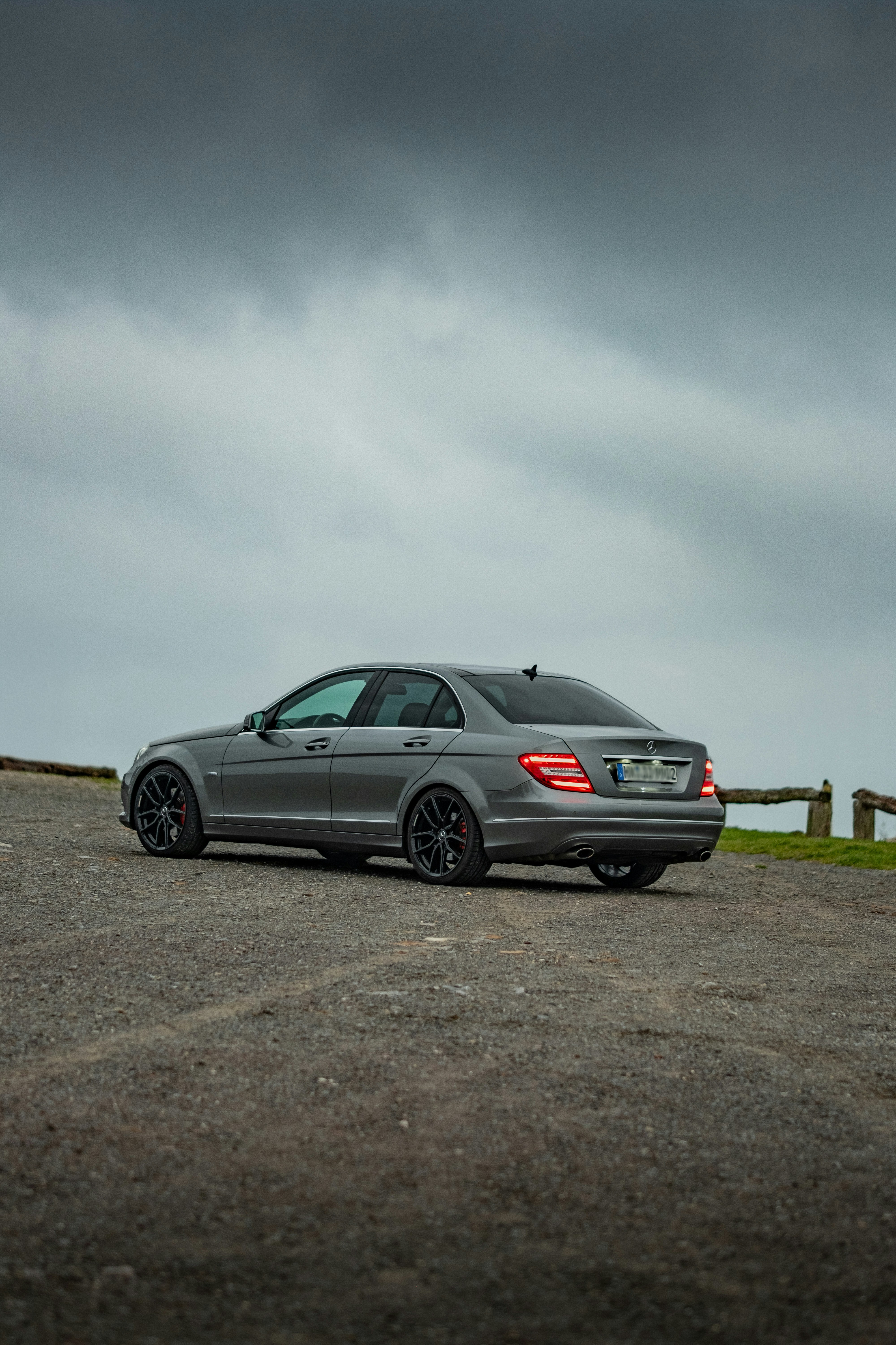 Eine graue Limousine auf einer Schotterstraße geparkt.