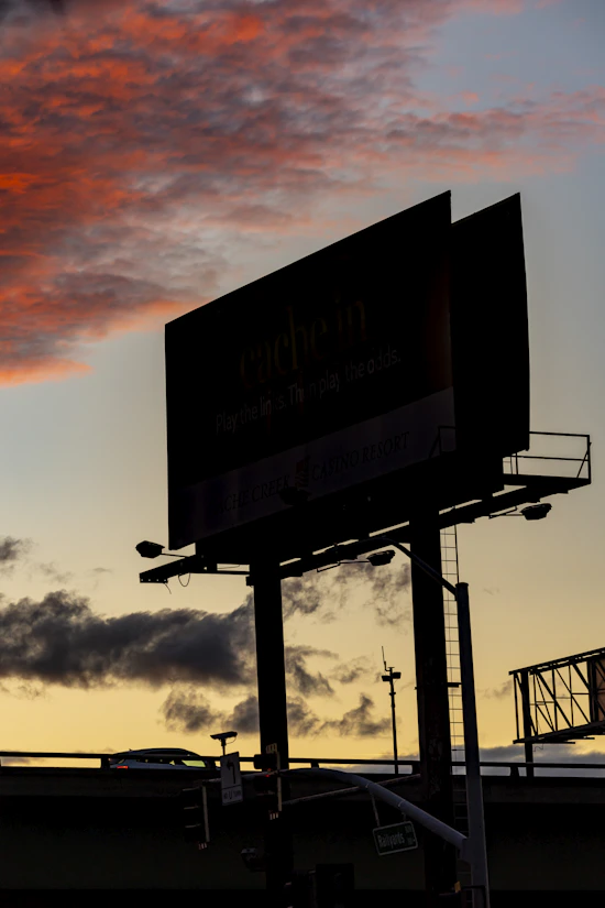 Silhouette of billboards against a dramatic sunset sky