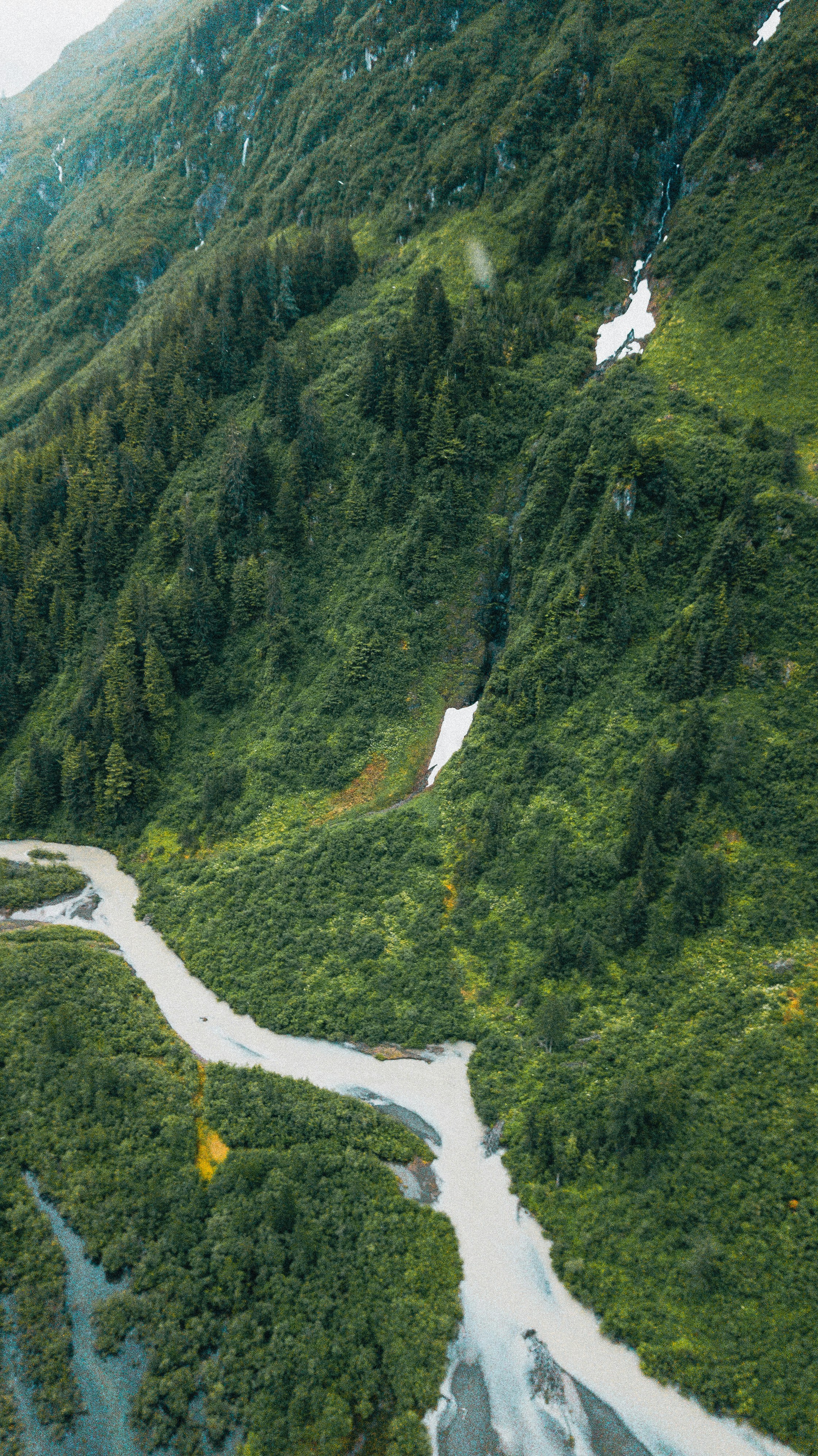 A winding river flows through a lush green mountain valley.