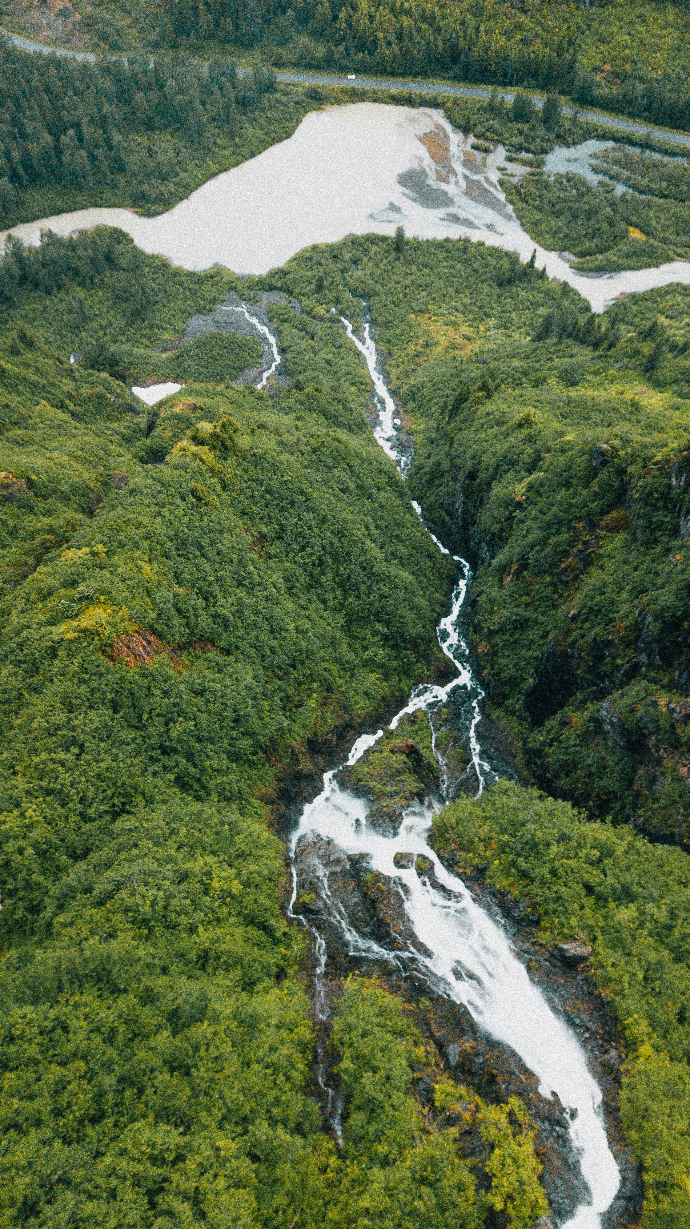 Aerial view of a cascading waterfall through lush green forest