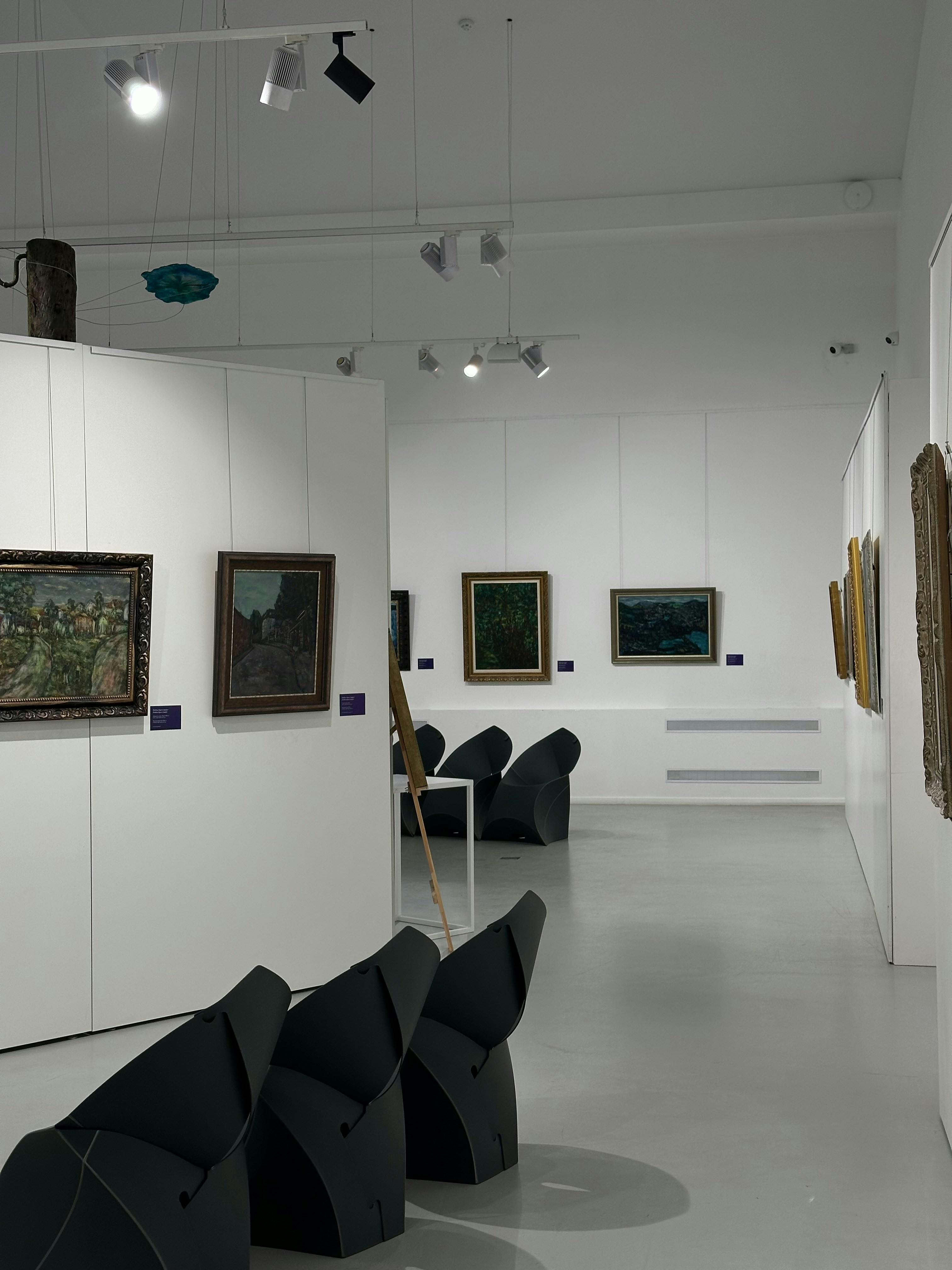 Interior galeri seni dengan lukisan dan tempat duduk