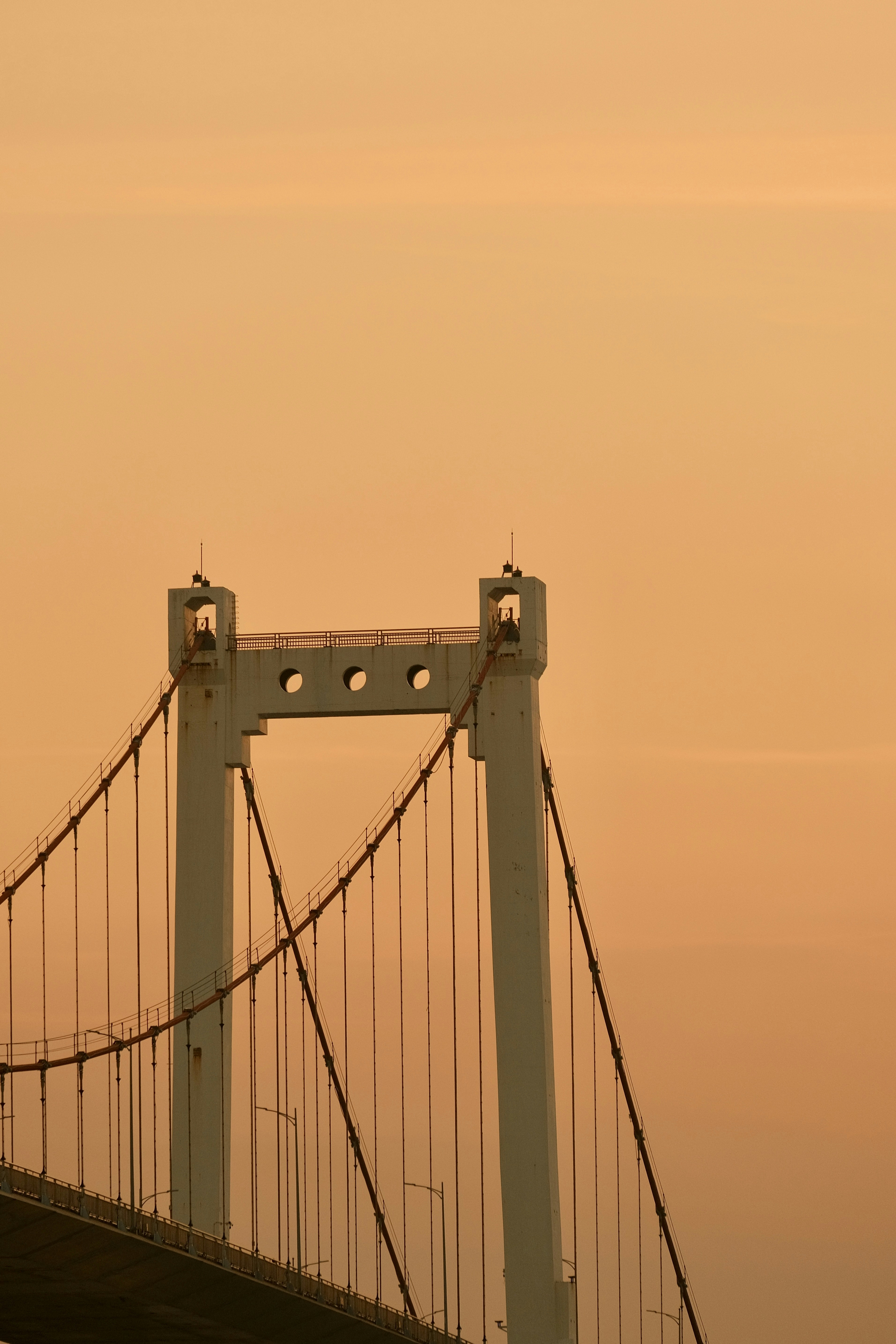 Suspension bridge tower against an orange sky