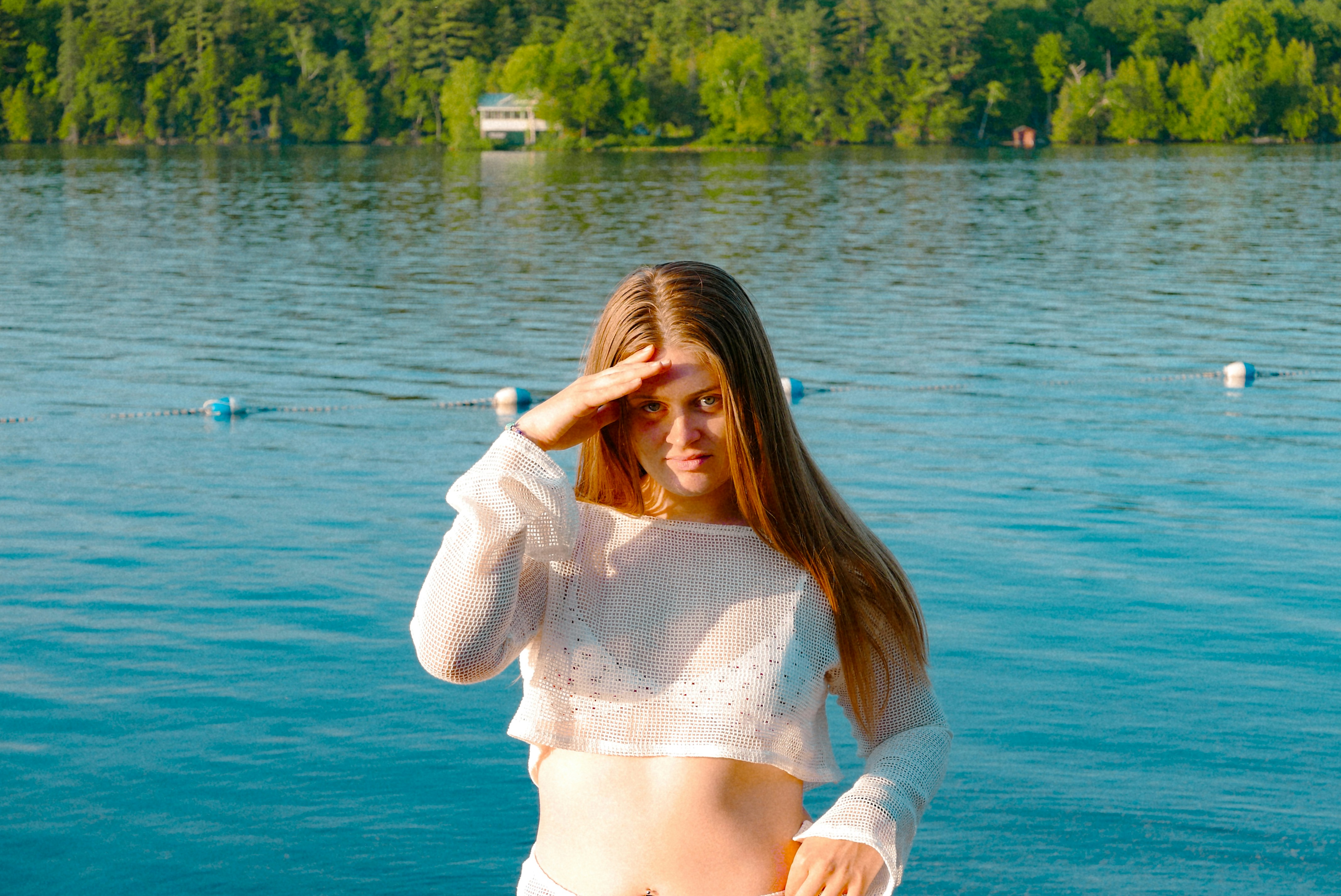 Young woman shielding eyes looking out at lake