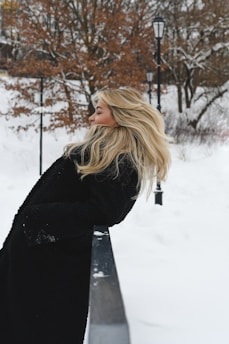 A blonde woman in a black coat in the snow