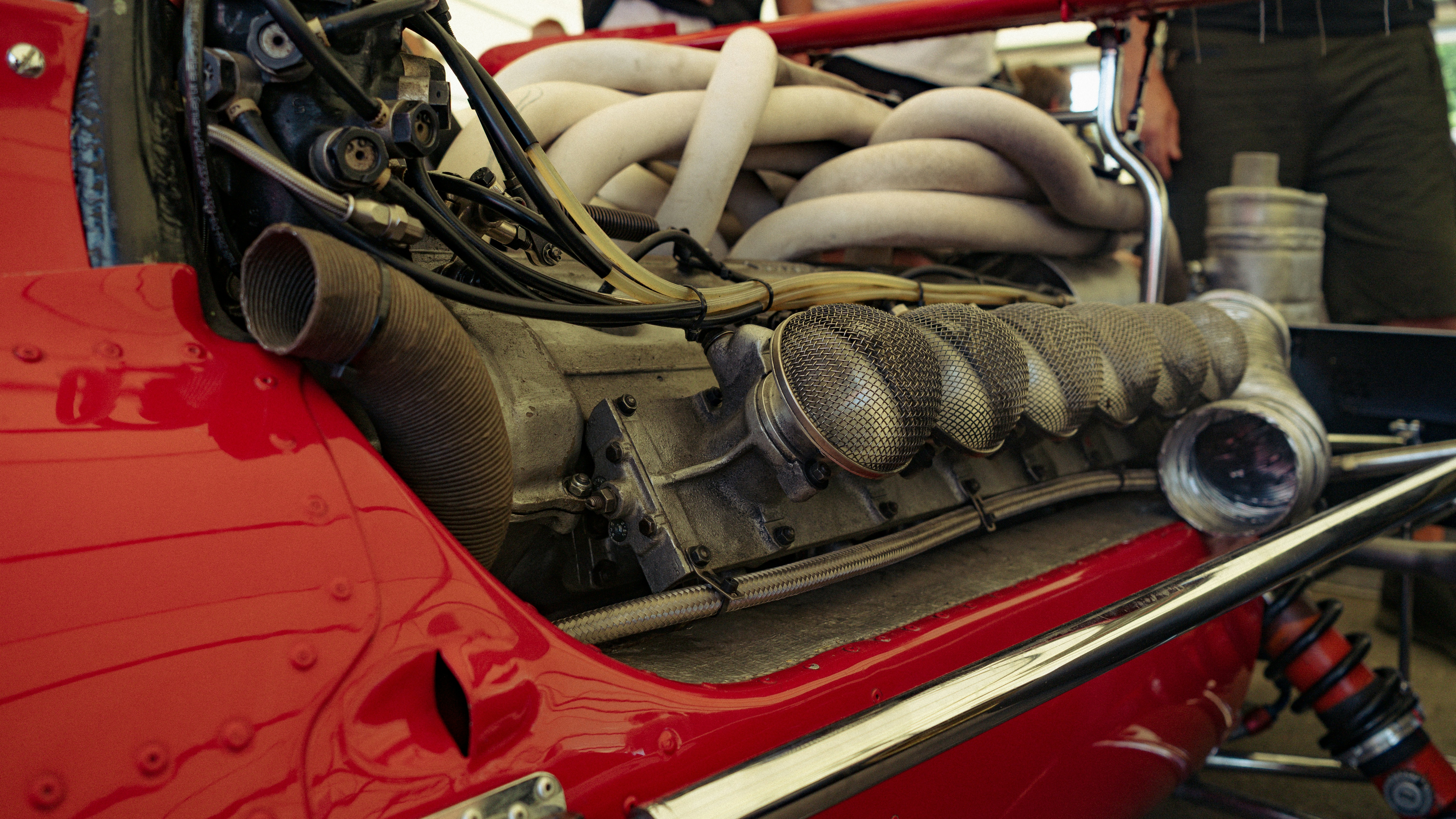 Close-up of a red race car engine with many pipes.