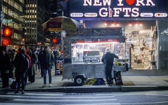 People gather at a street food cart at night.