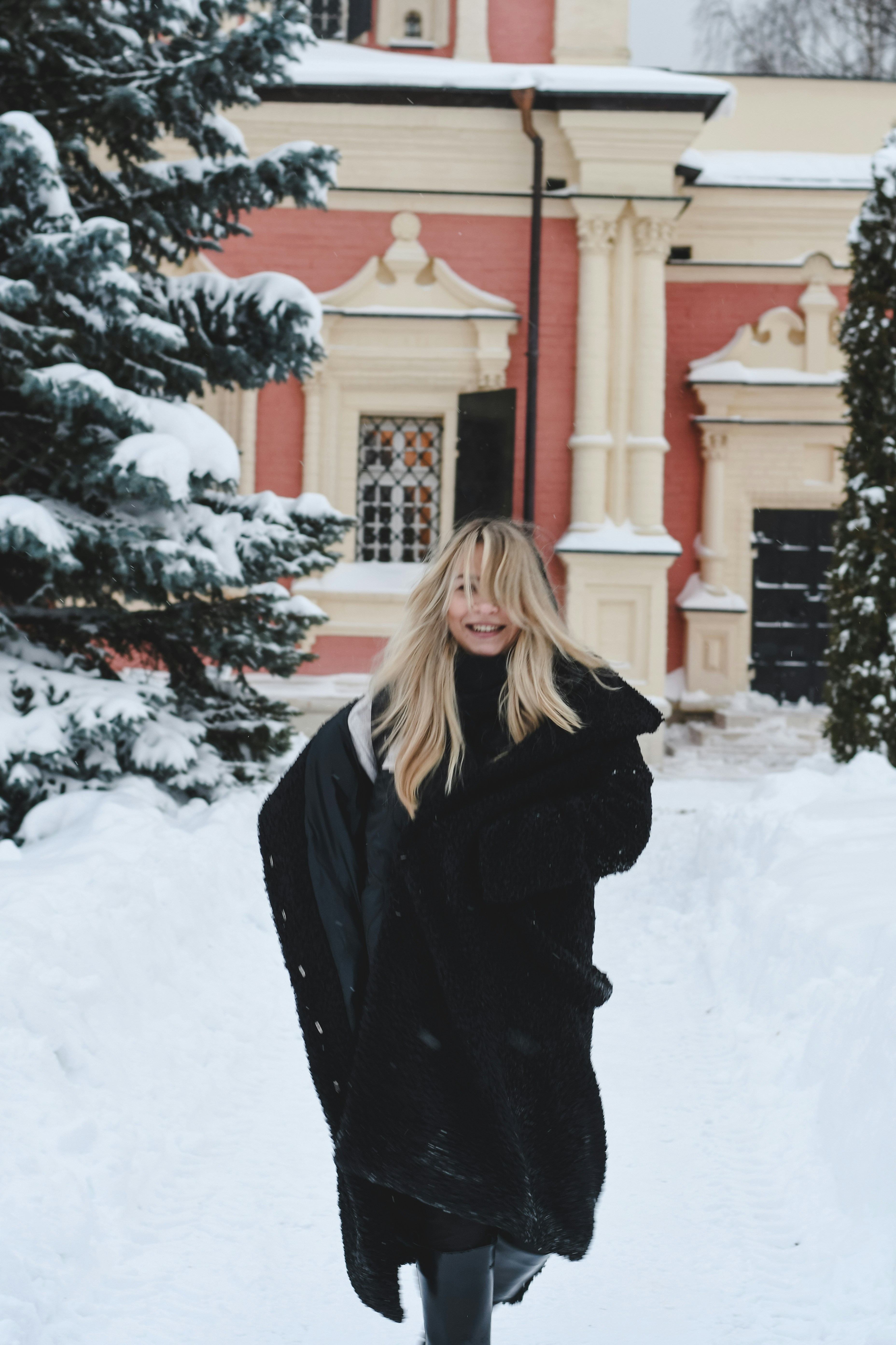 A woman in a black coat walks through snow