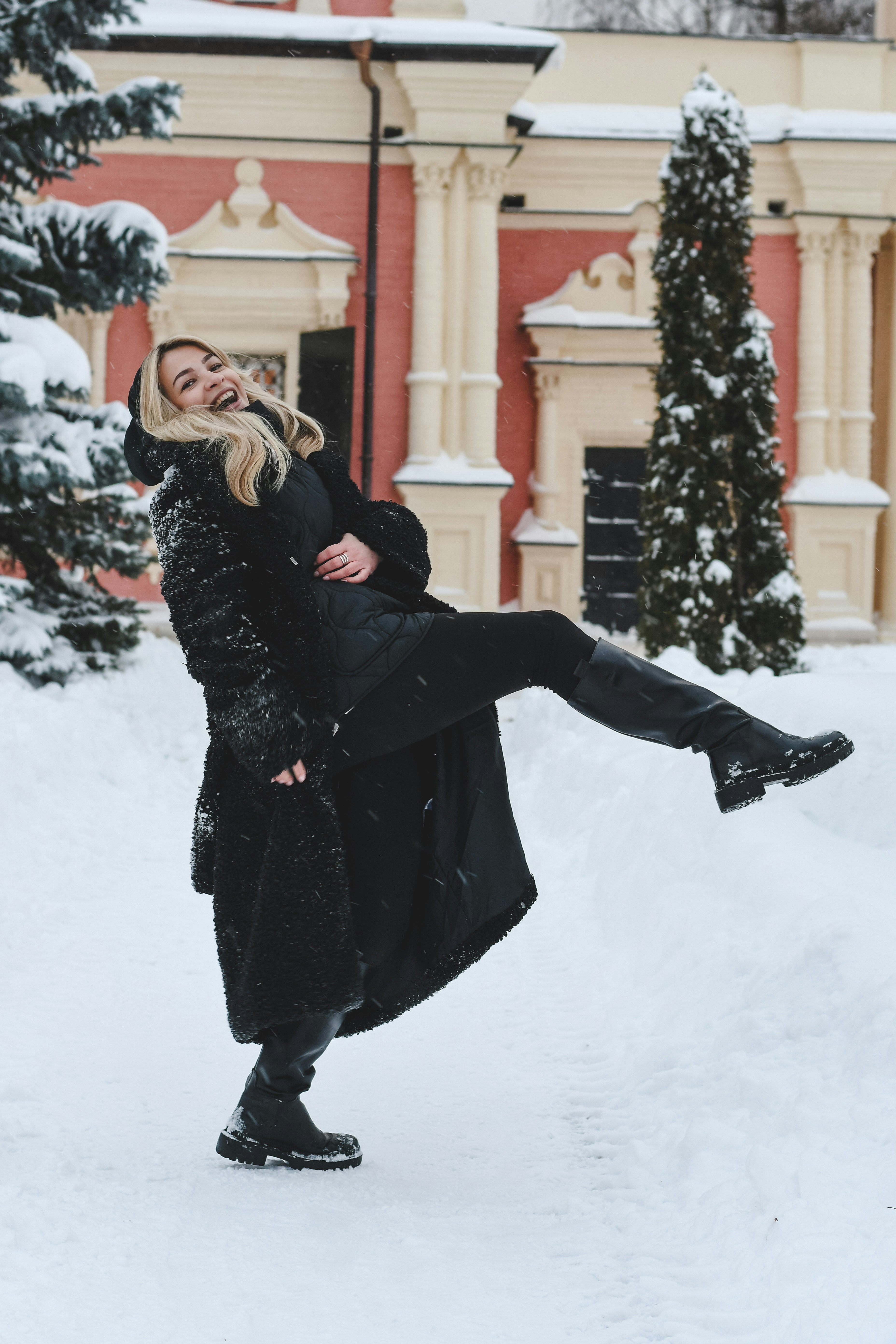 A happy woman in a black coat in the snow