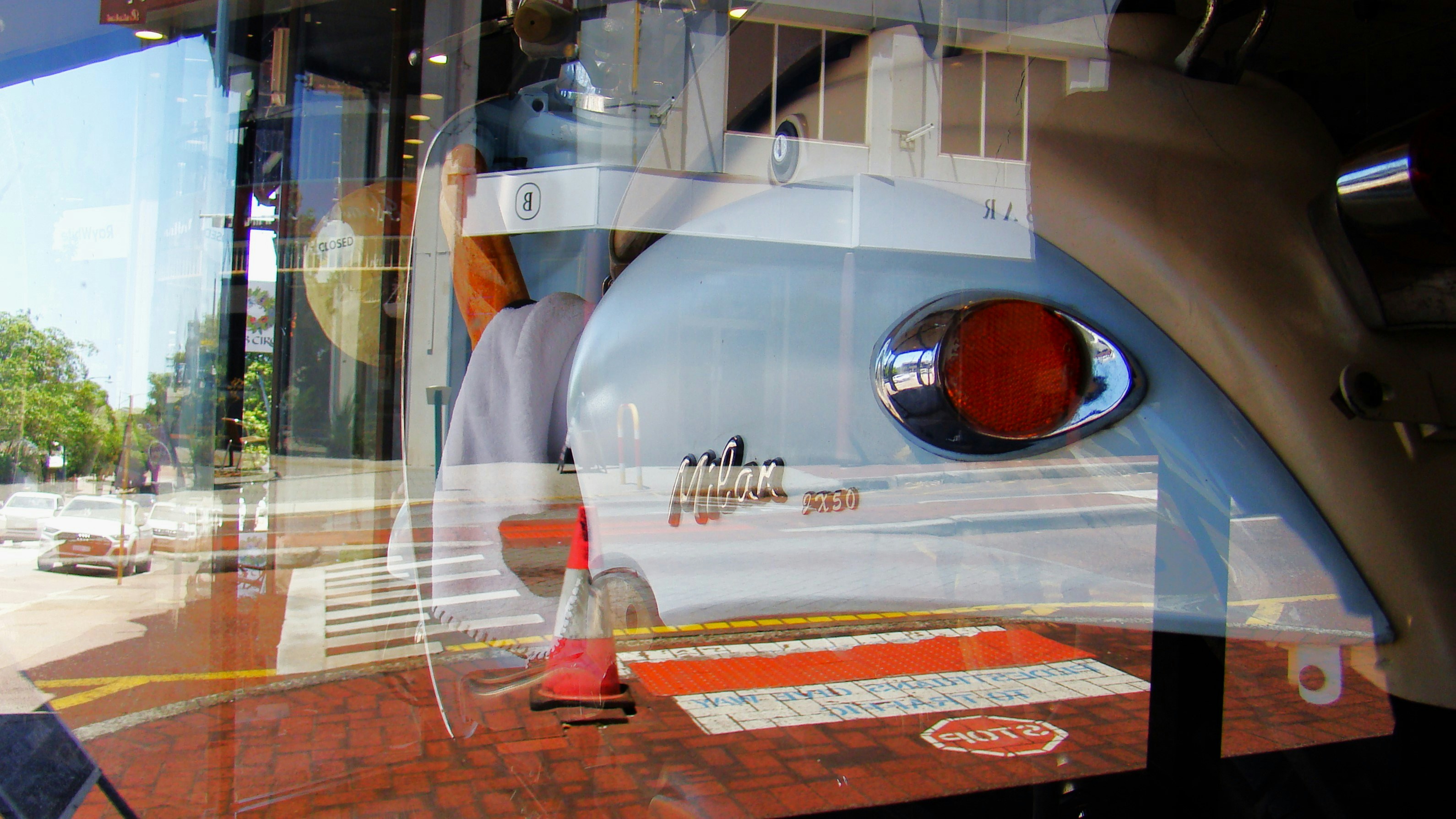 Riflesso di uno scooter d'epoca in una vetrina di un negozio.