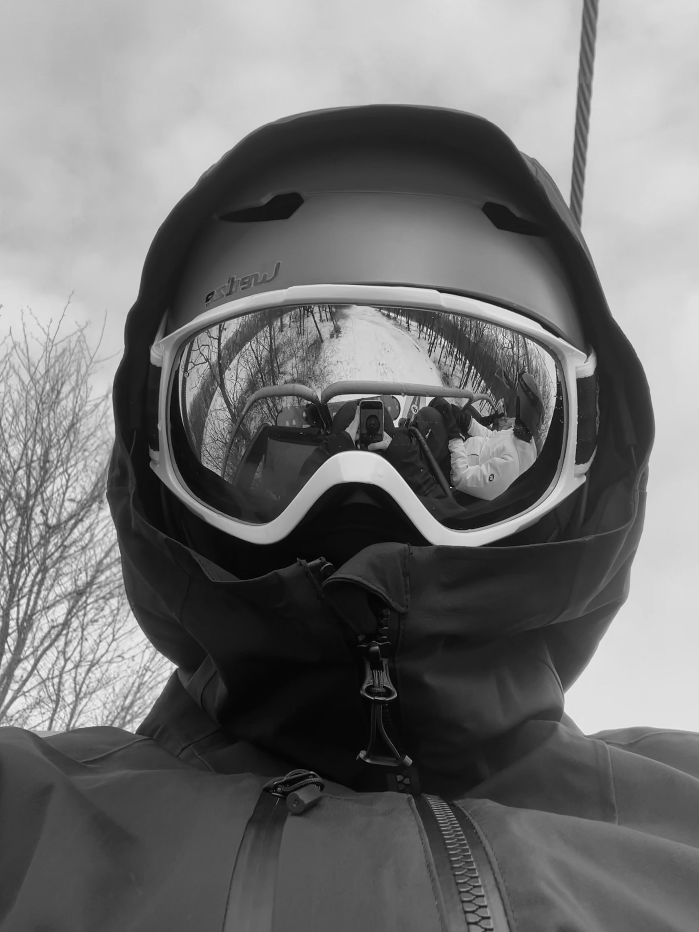 Person in ski gear with goggles reflecting landscape