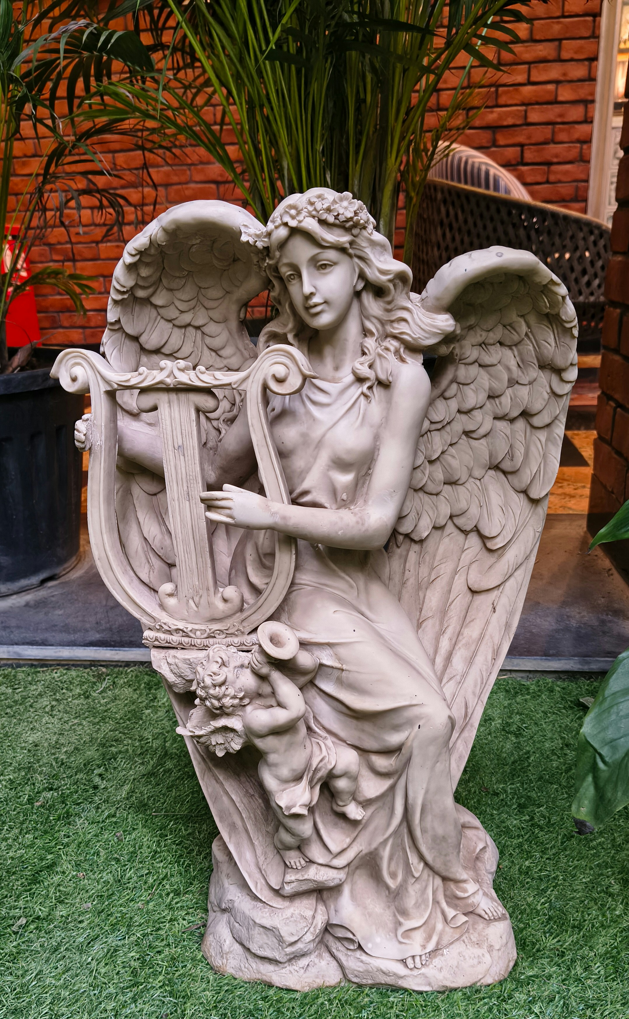 Stone angel statue with harp and cherub on grass.