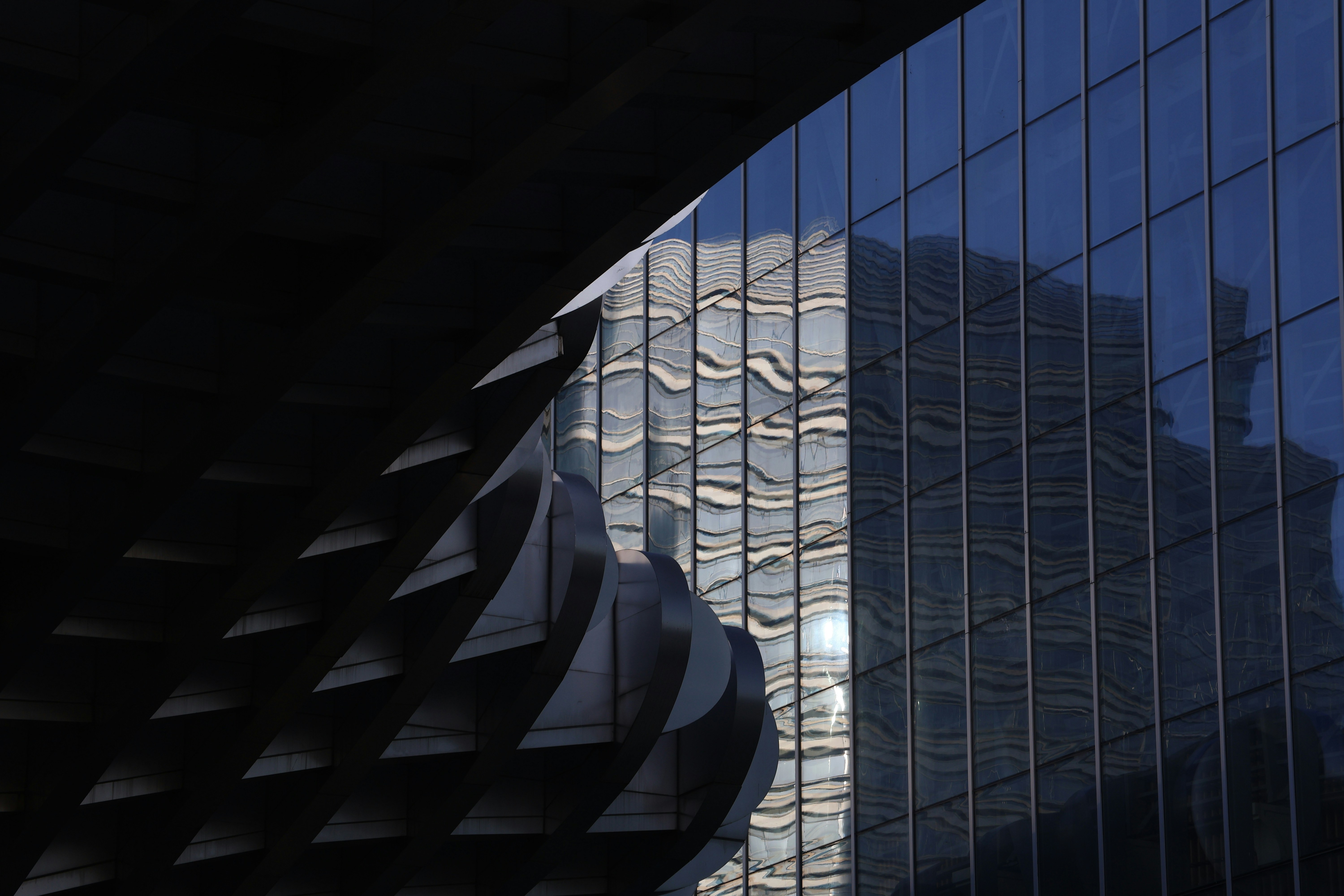 Modern building facade reflecting distorted buildings and sky.