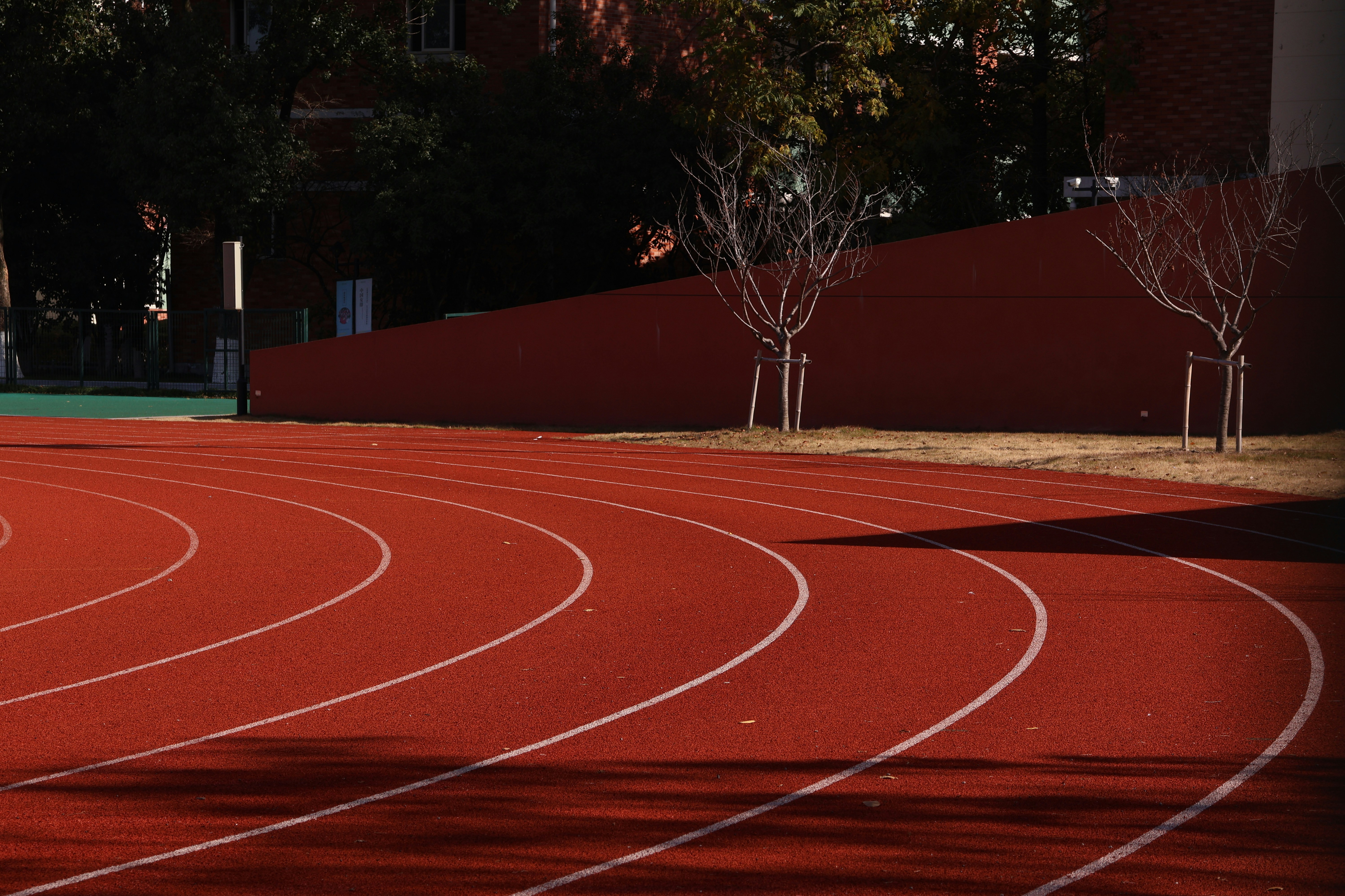 Curving red running track with white lane lines
