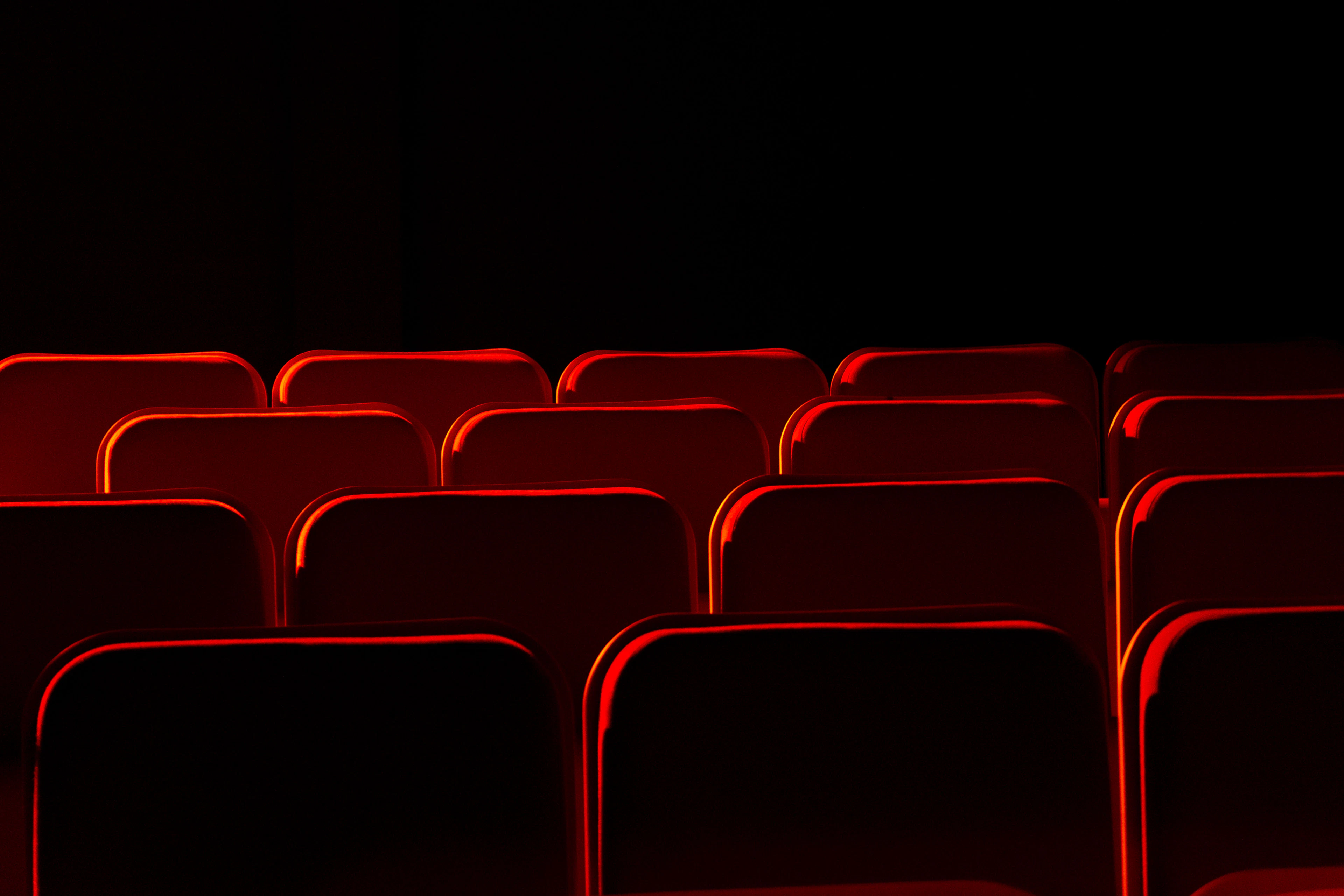 Rows of empty red theatre seats in darkness