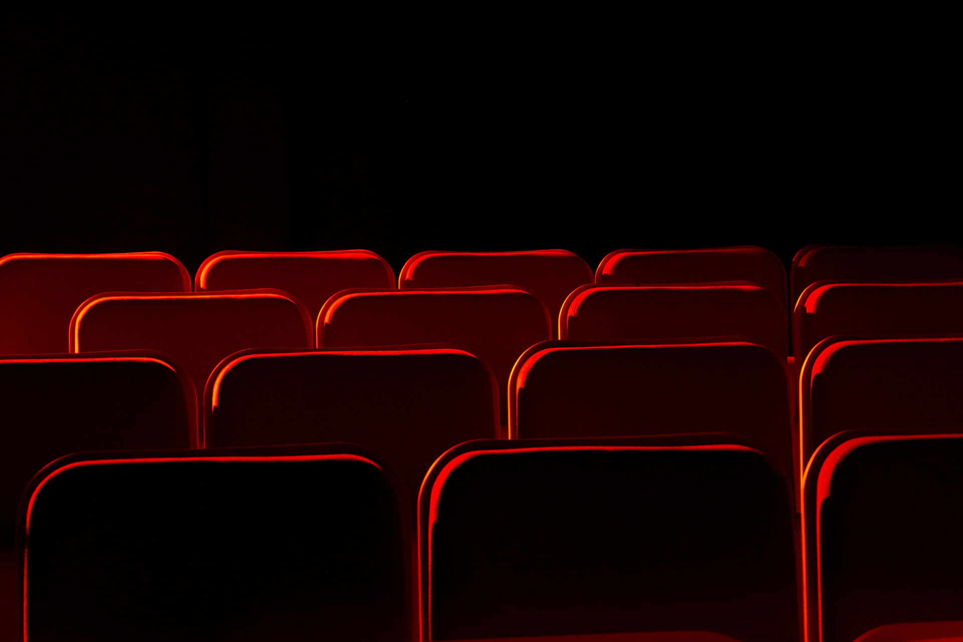 Rows of empty red theater seats in darkness