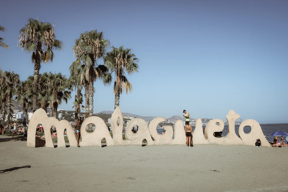 Large letters spell out malaga on a sandy beach.