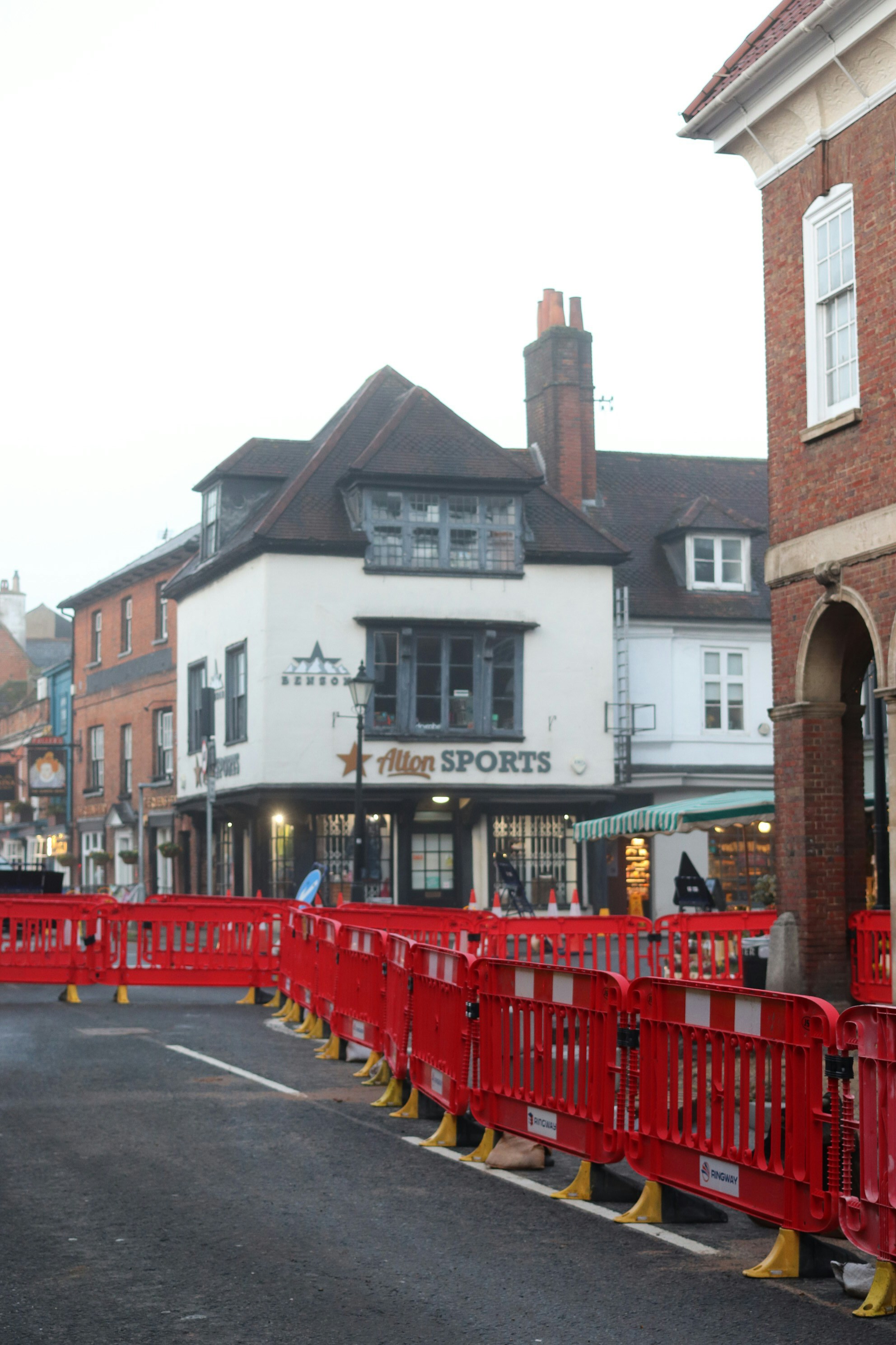 Red barriers line a street in front of buildings.
