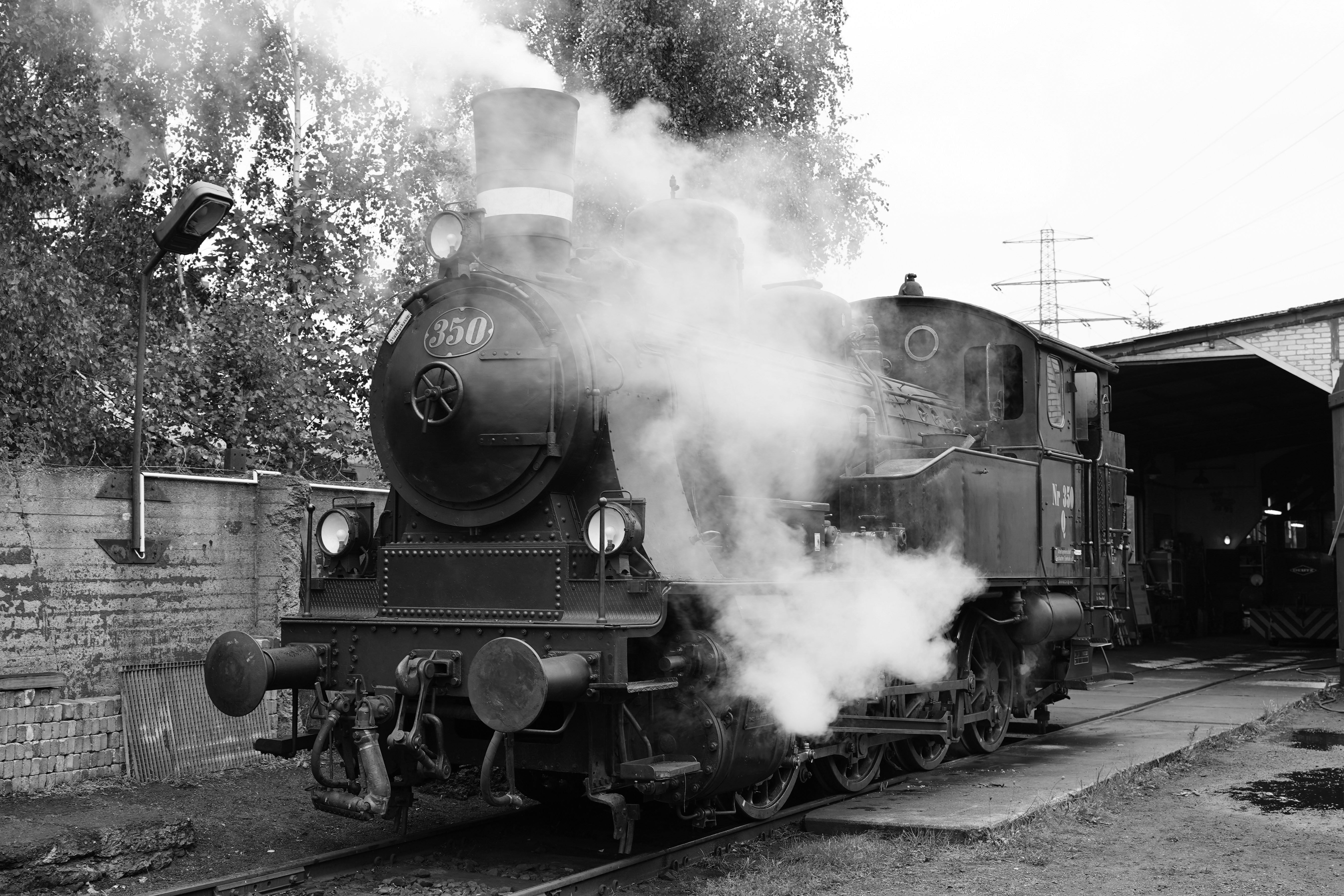 Steam locomotive emitting smoke near a building