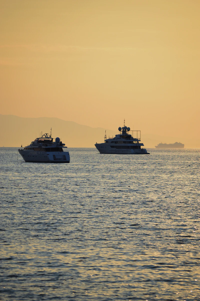 Two superyachts lying at anchor in calm water at sunset off the French Riviera
