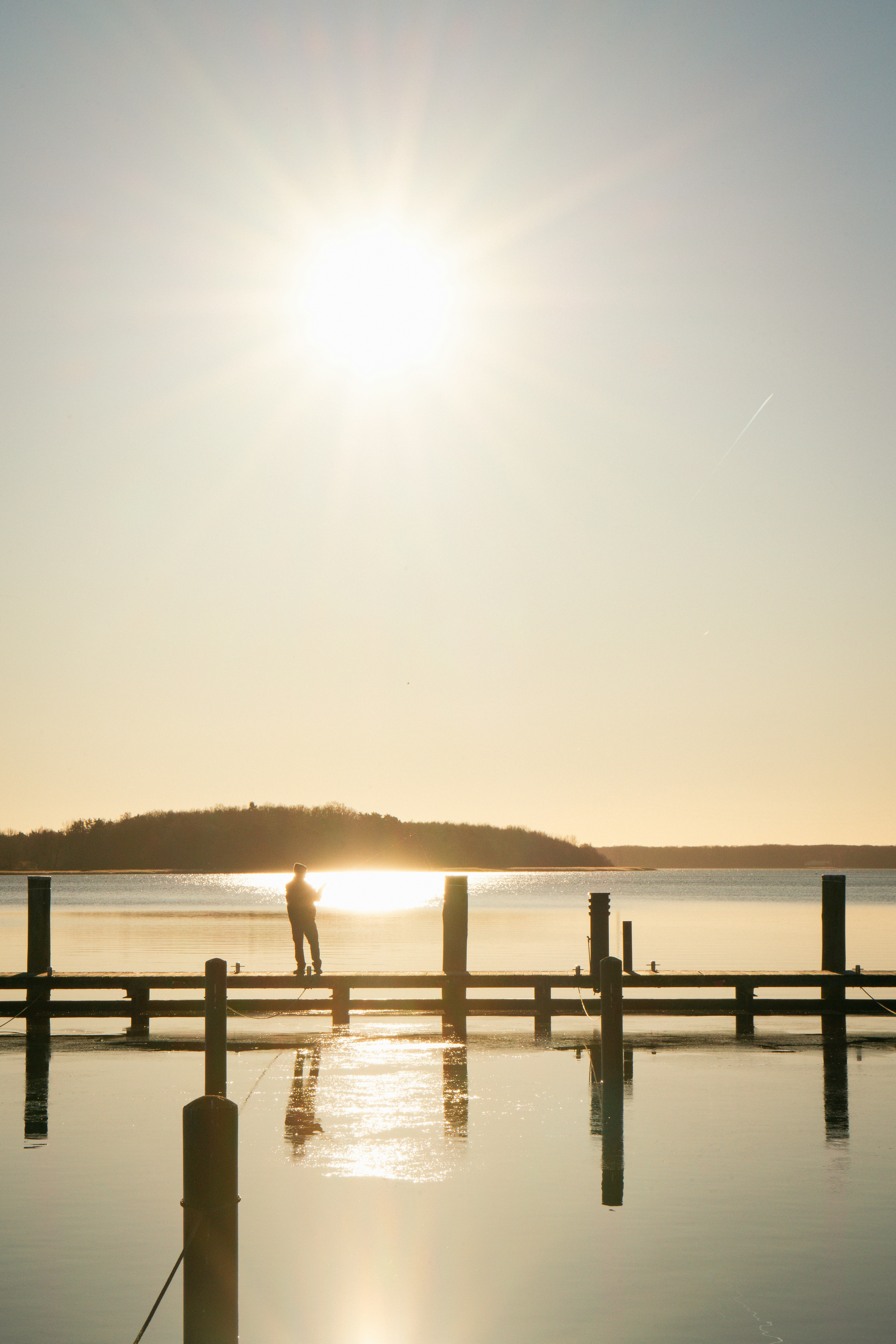 Man fishing from a pier at sunset