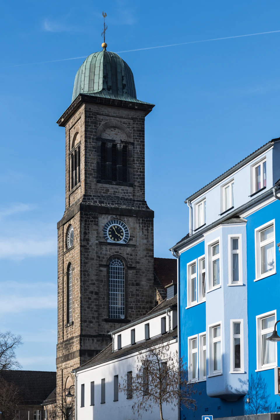 The image depicts a serene cityscape with two distinct buildings, one blue and white and the other brown and gray. The blue building features a clock tower on its left side, while the brown and gray building has a smaller clock face on its right side. Both buildings have large windows that reflect the clear blue sky above. In front of the blue building, there is a tree with lush green leaves, adding a touch of nature to the urban setting.

The image also contains some text elements, including "sa_1296" and "sa_1297", which may be reference numbers or identifiers for specific locations within the city.