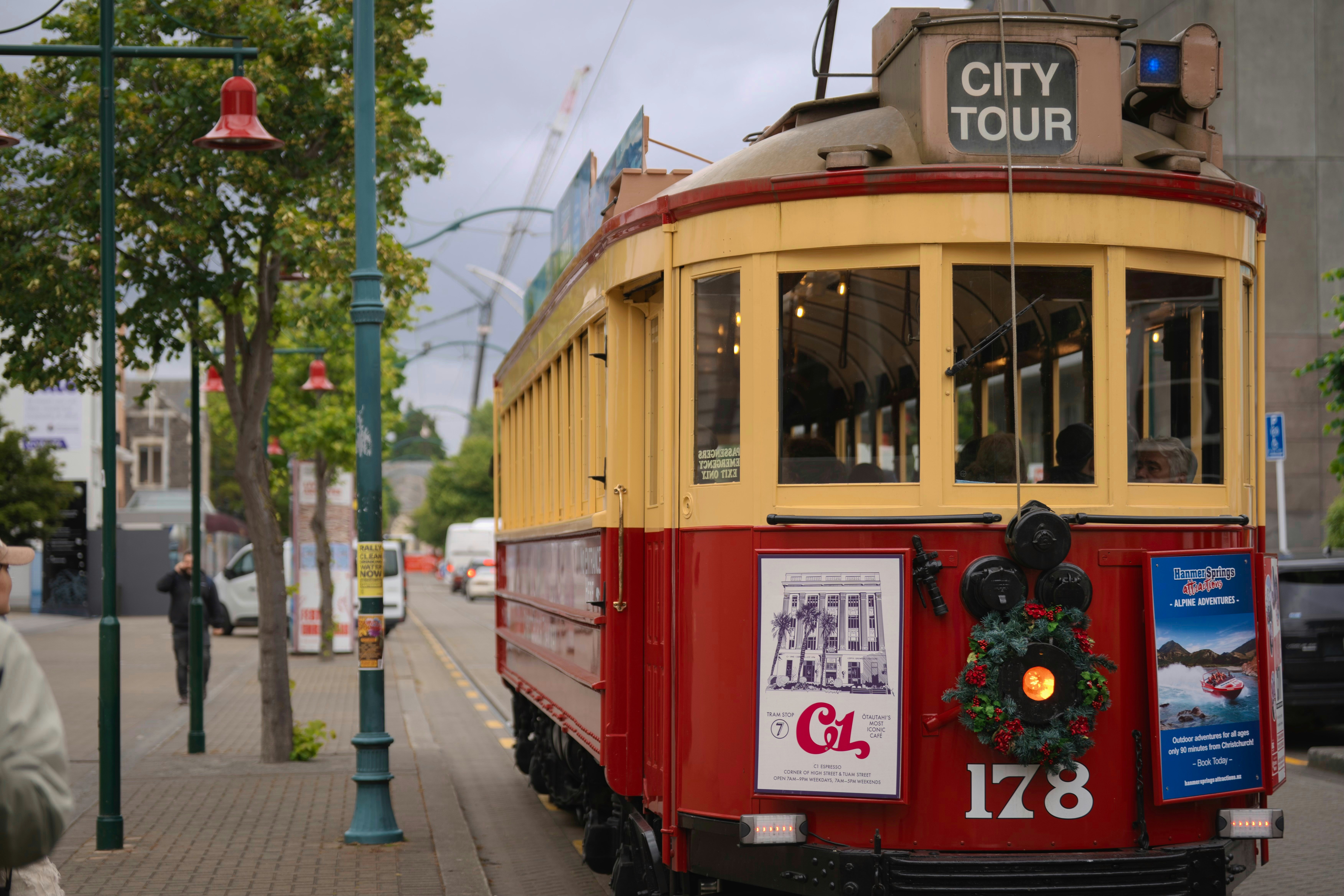 A vintage red and yellow city tour tram on tracks.