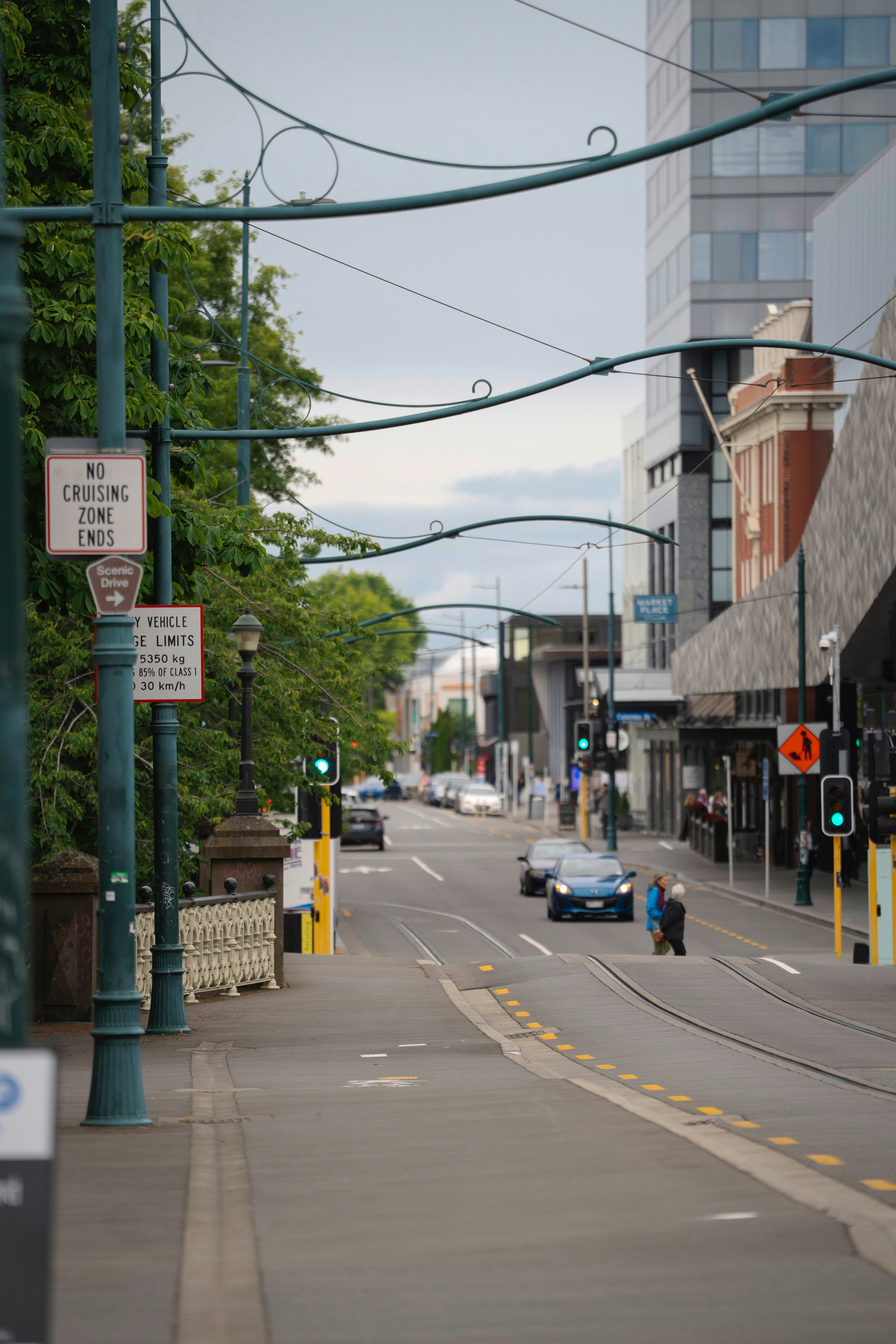 Cars driving down a city street with tram tracks.
