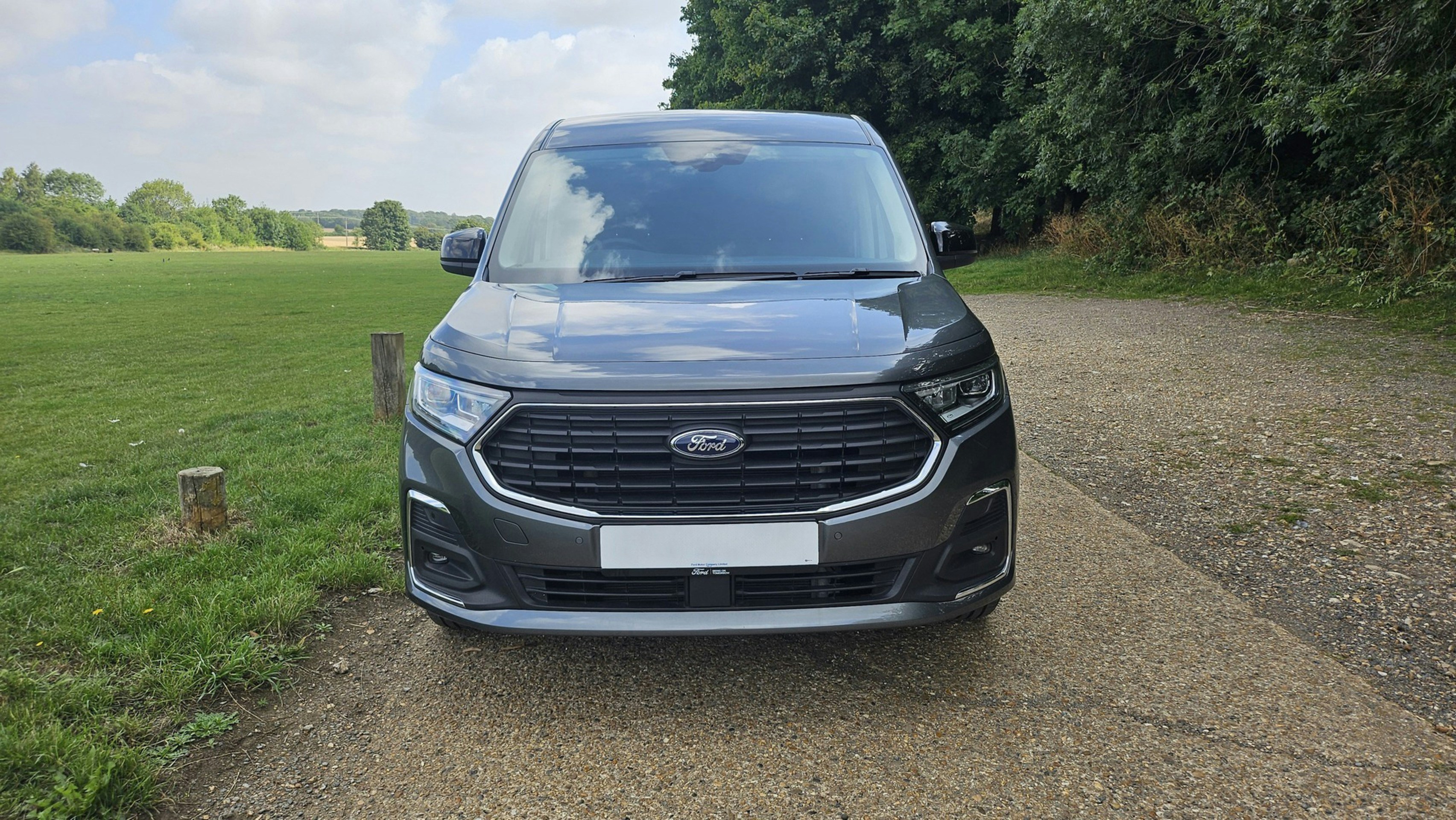 Dark grey van parked on gravel path outdoors.