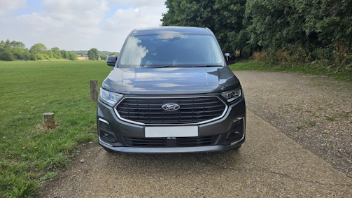 Dark grey van parked on gravel path outdoors.