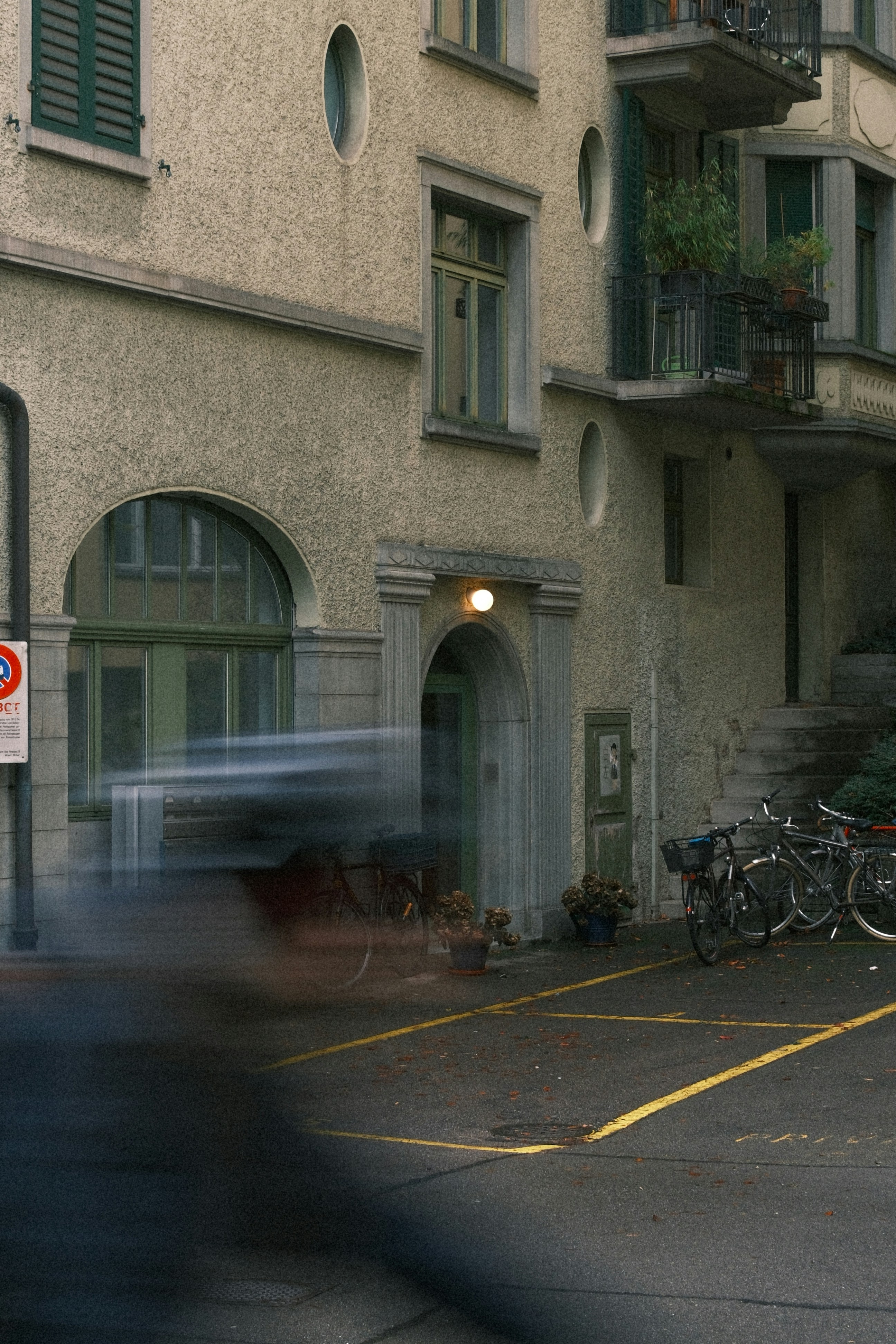 Blurry car passing by a building with bicycles.