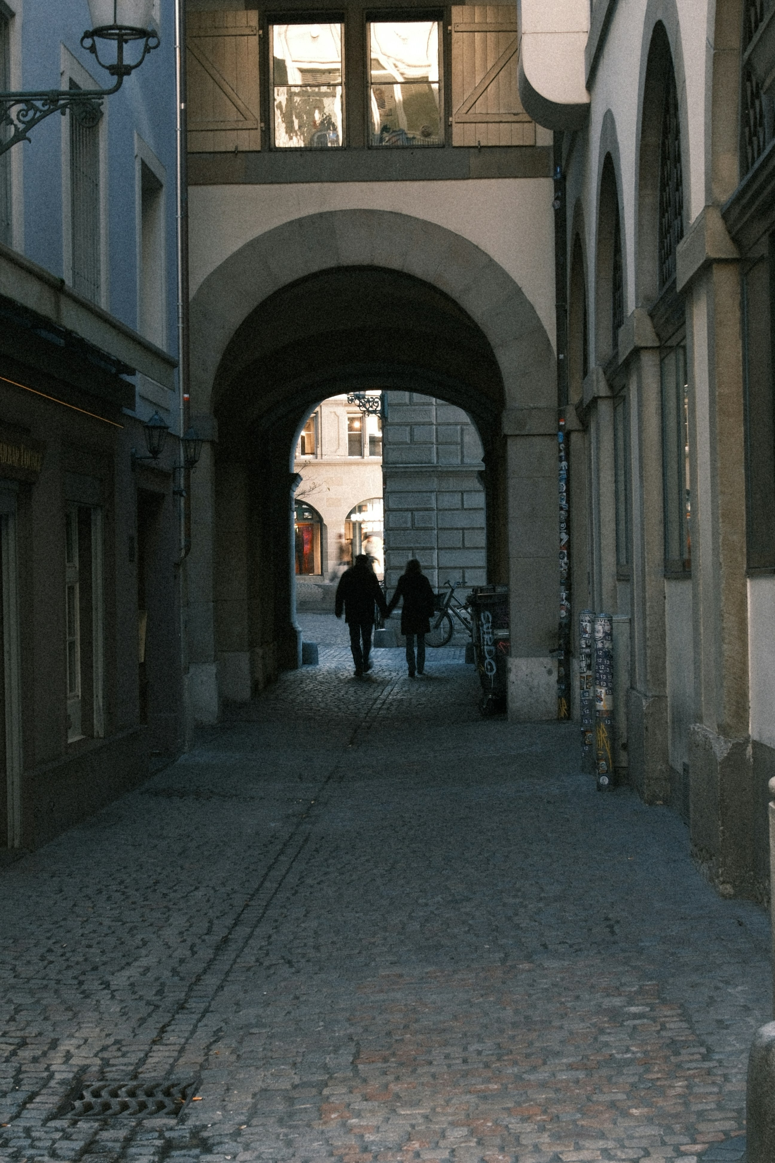 Un couple traversant une vieille arche en pierre.