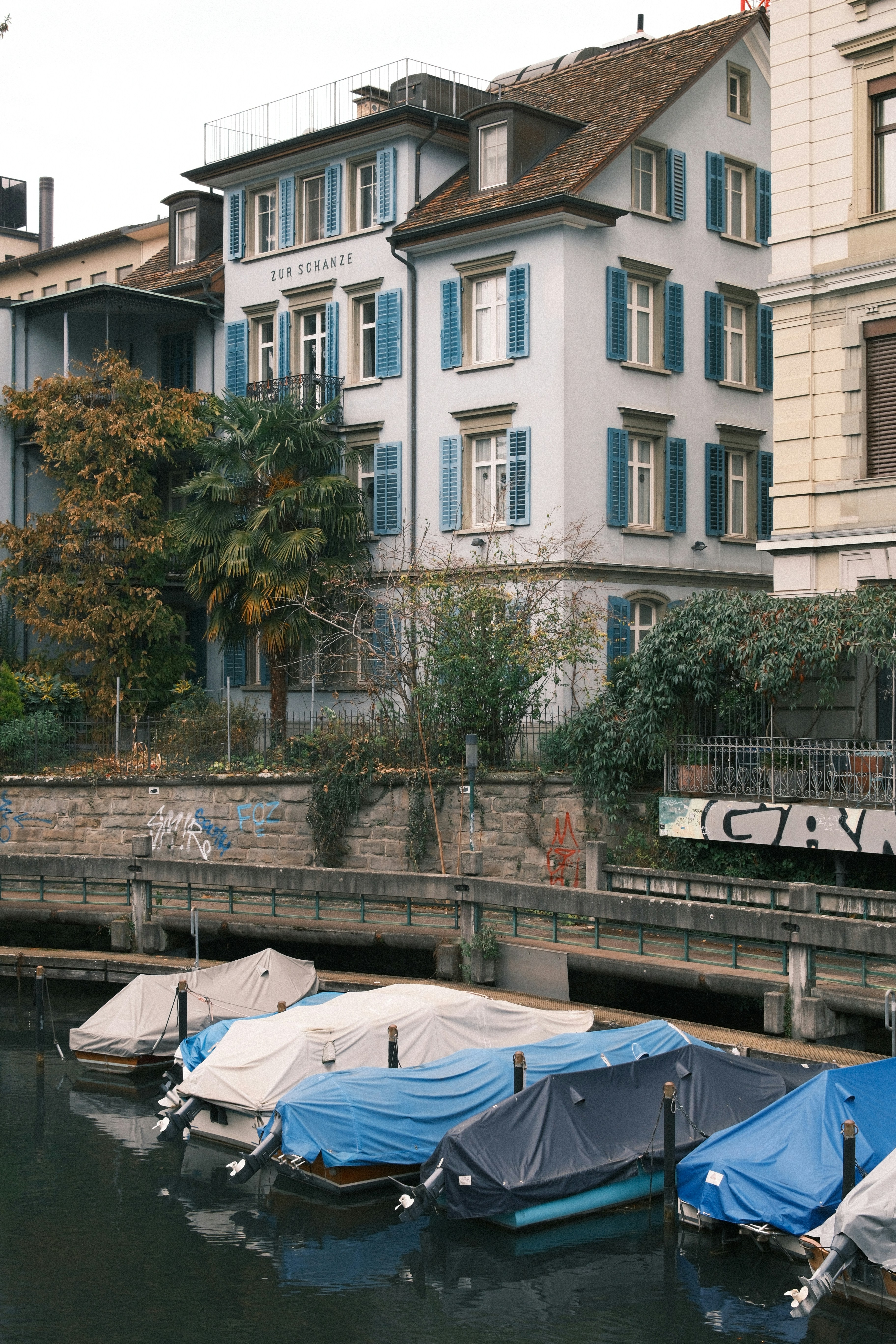 Des bateaux recouverts de bâches amarrés près d’un bâtiment.