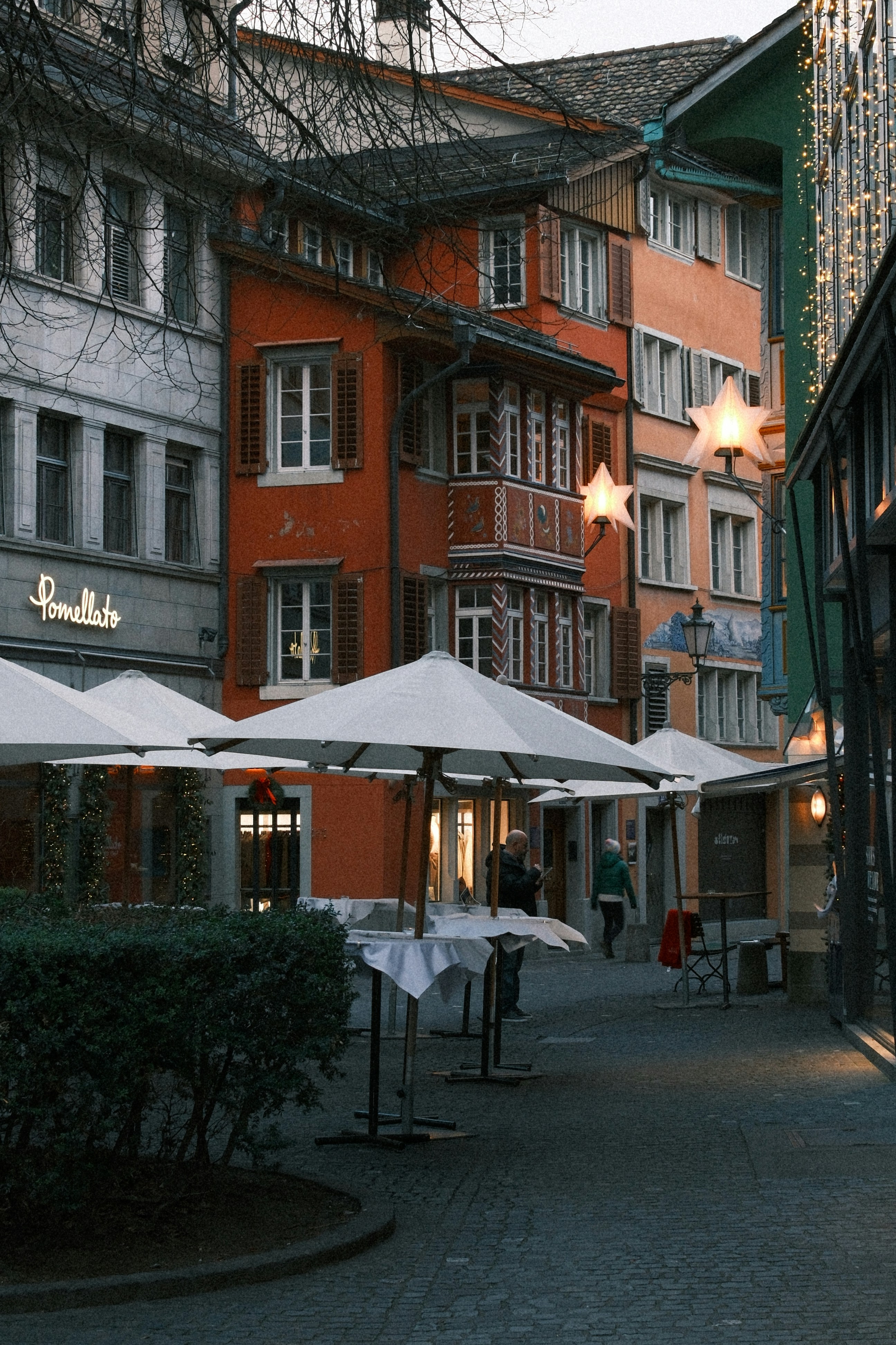 Des bâtiments colorés bordent une rue européenne avec des places extérieures.