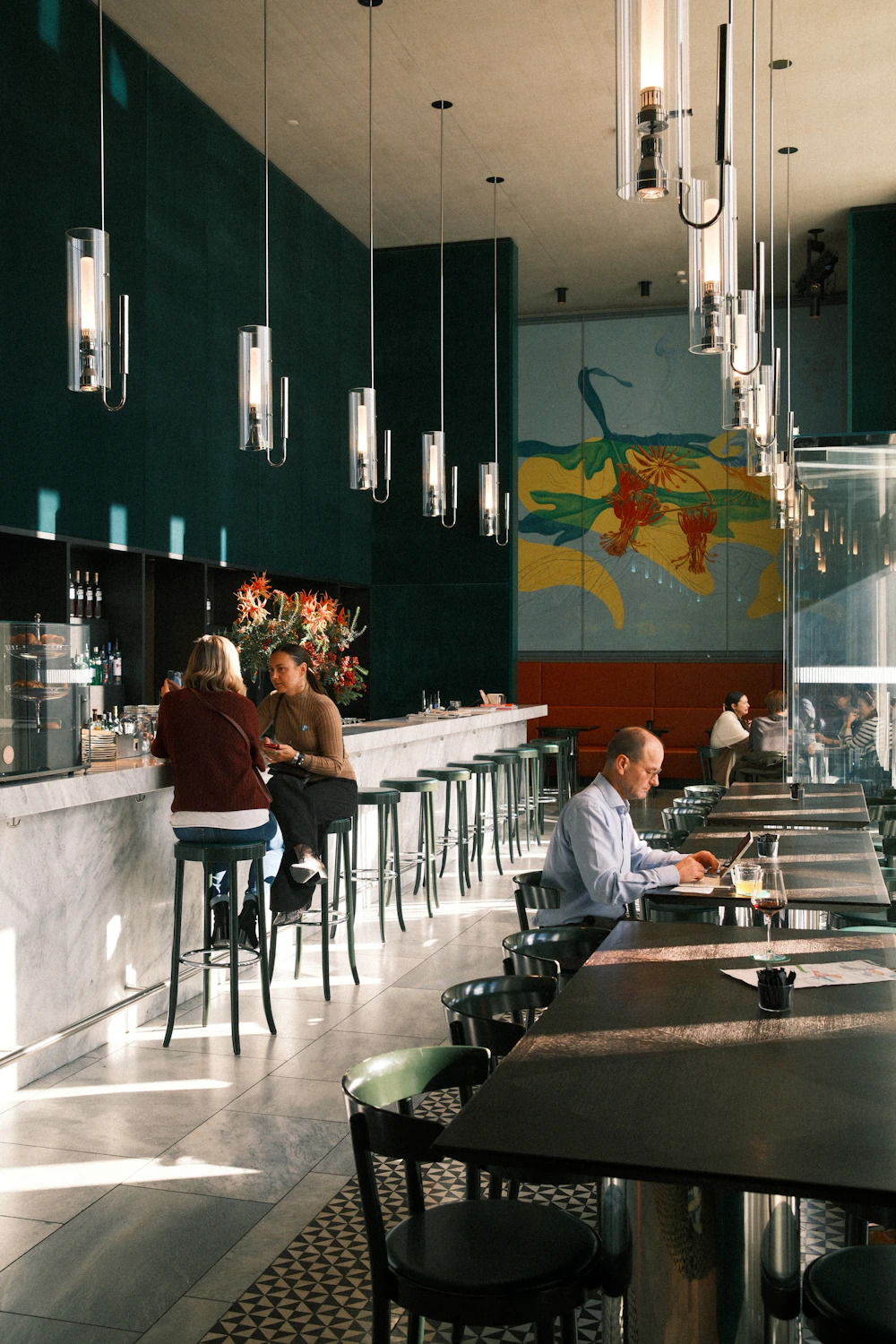 Diners at a modern restaurant bar under glass pendant lights