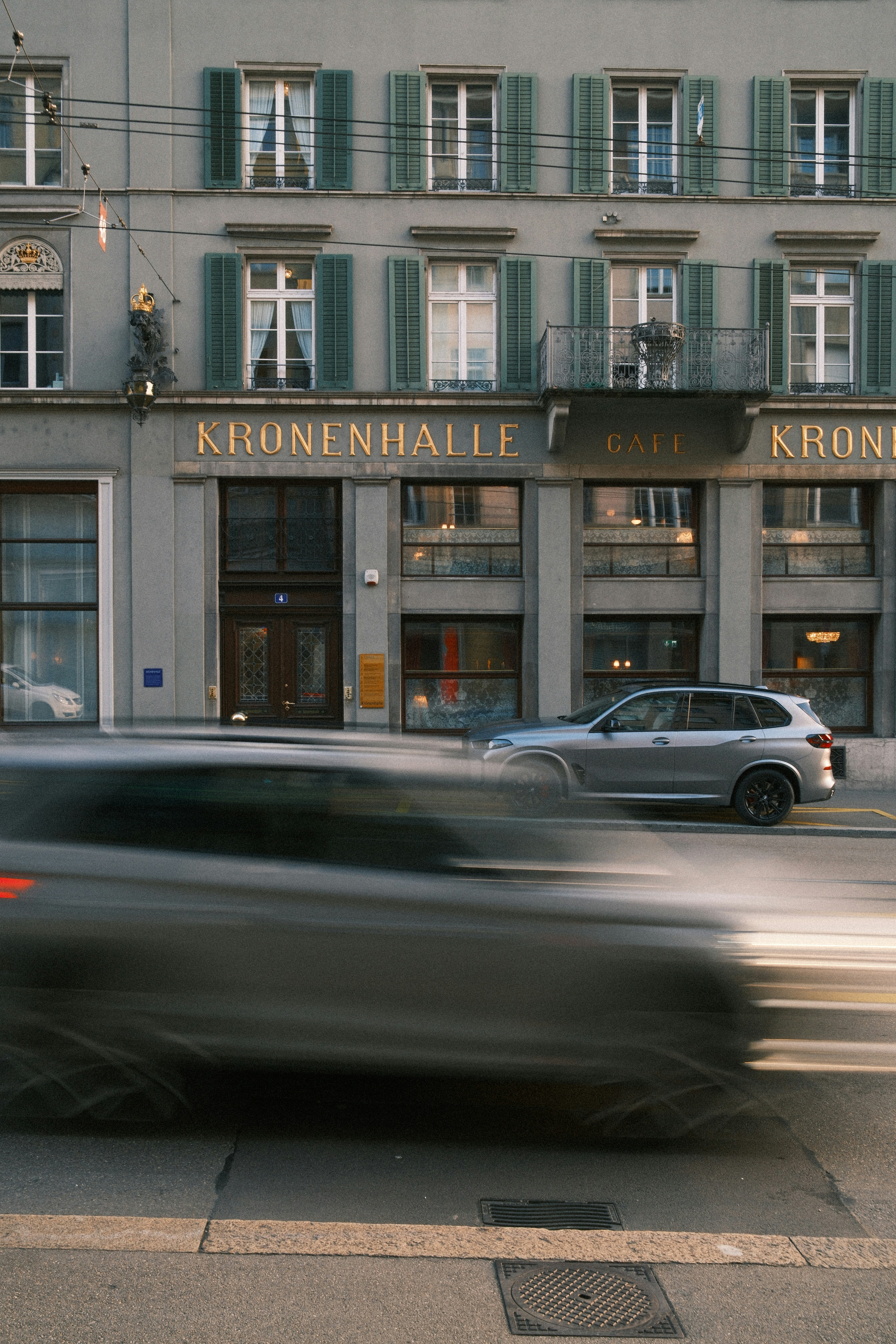 Des voitures passant devant un bâtiment avec un panneau « kronenhalle ».