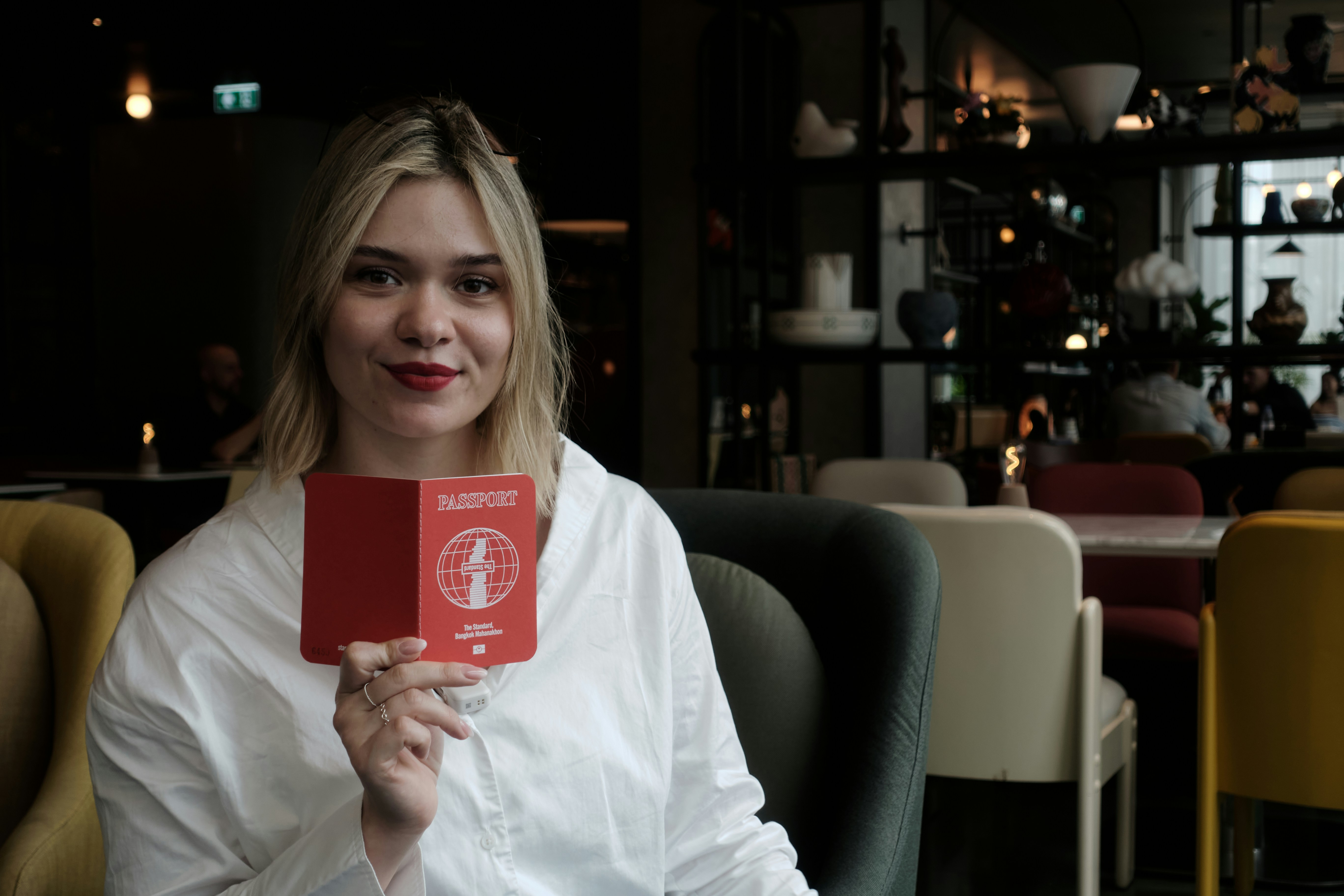 Young woman holds up a red passport