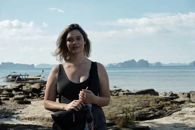 Woman standing on rocky shore with ocean and islands behind