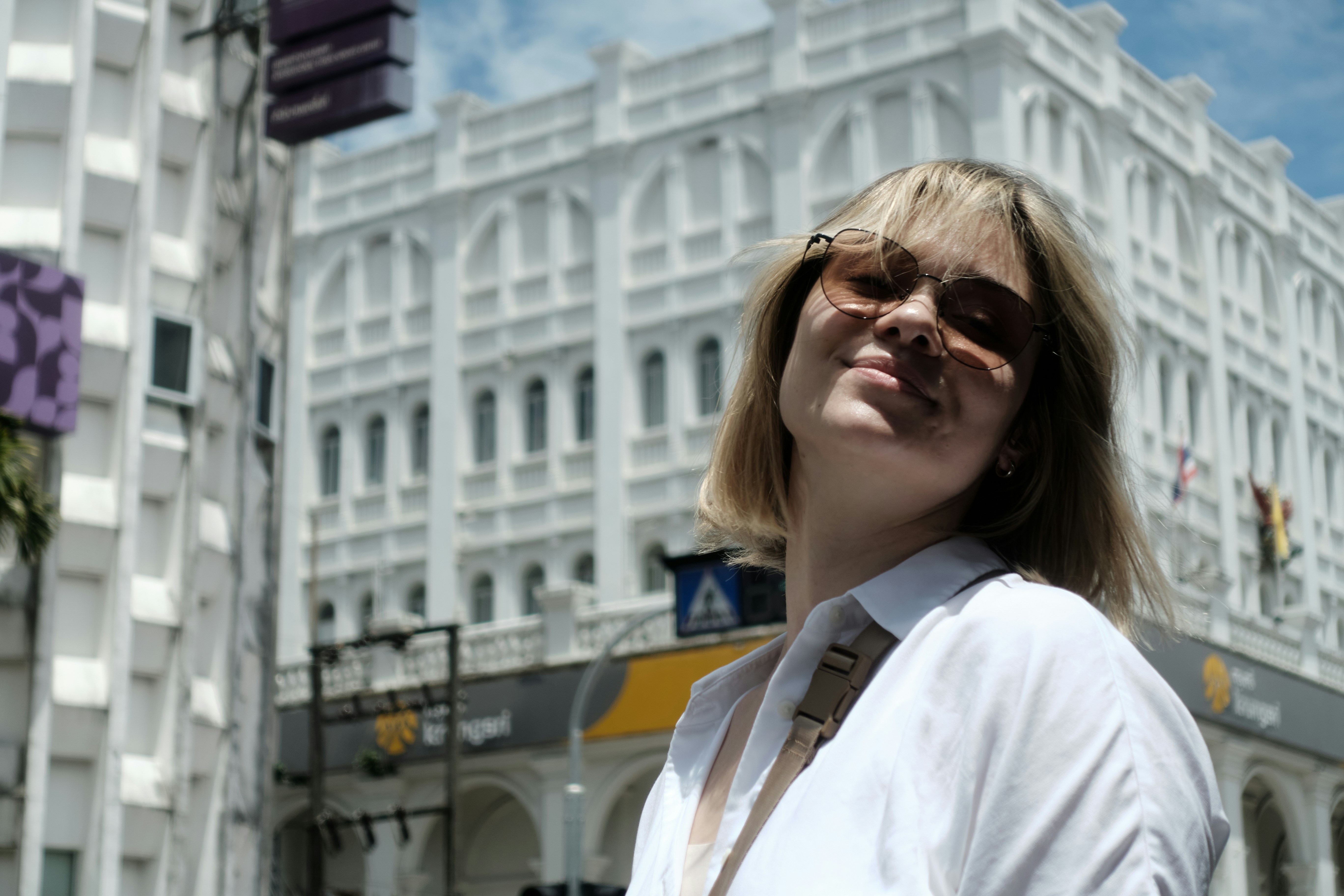 Eine junge Frau lächelt vor einem weißen Gebäude.