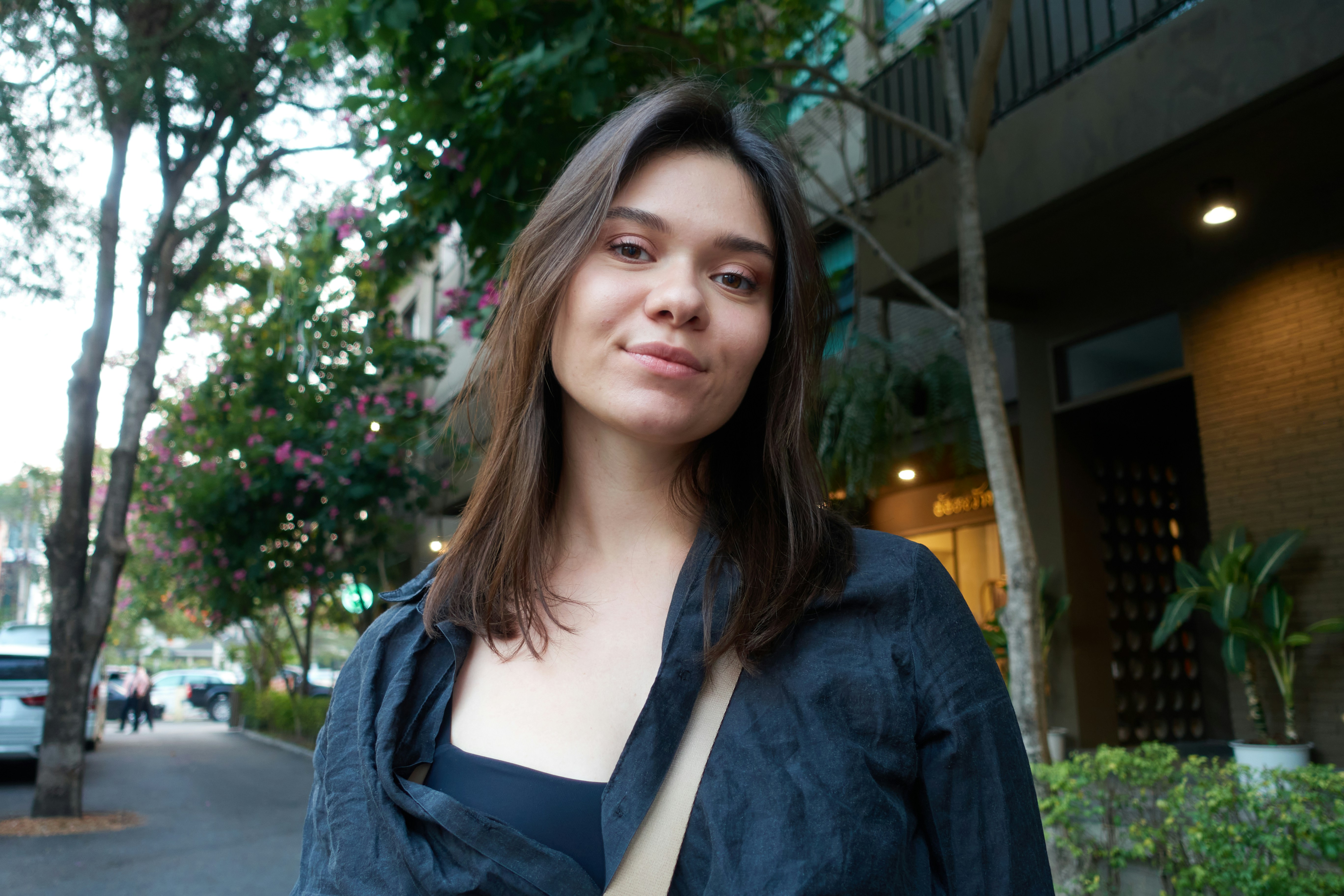 Young woman with dark hair smiles outdoors