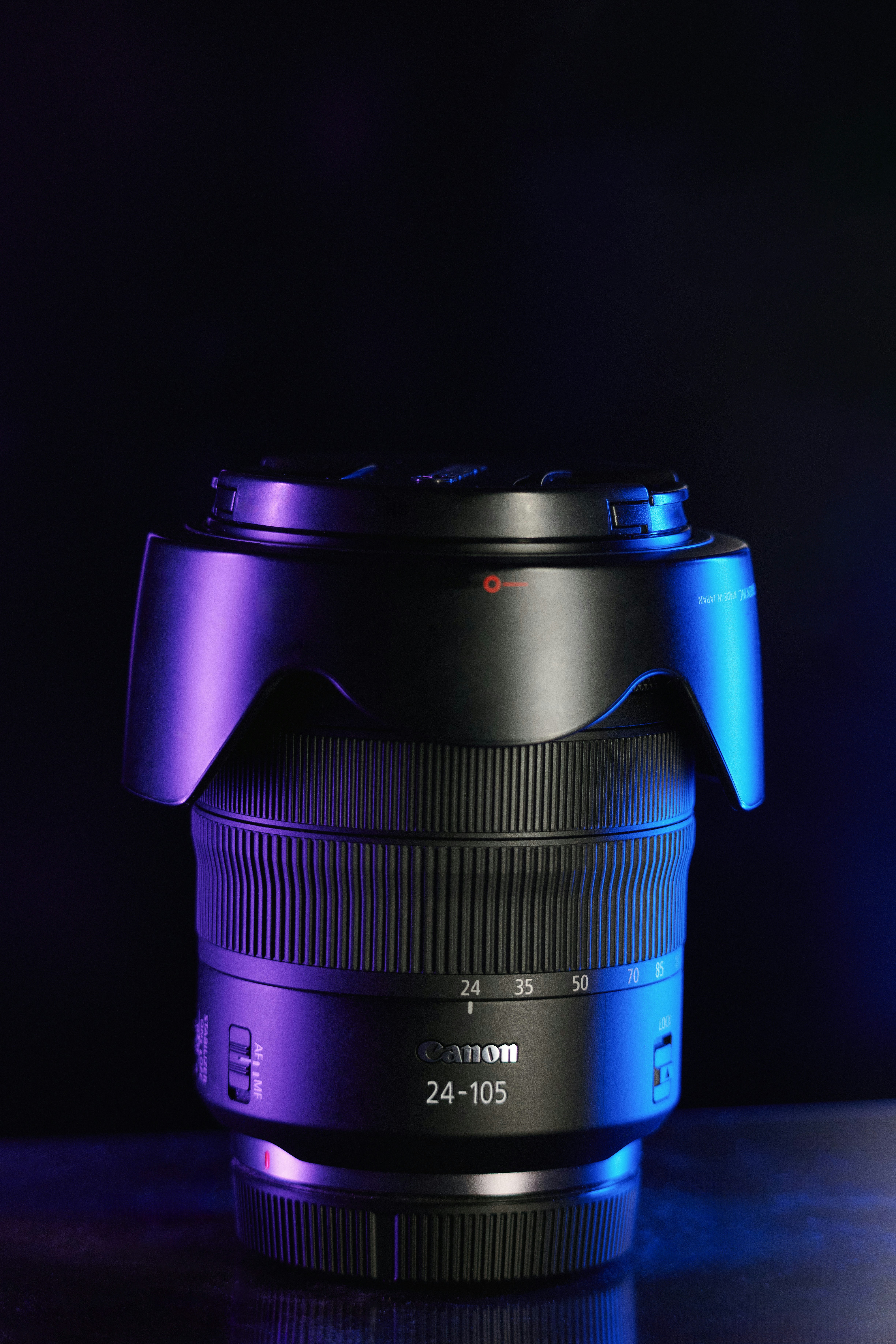 紫と青のライトが入った黒いキヤノンカメラレンズ。
