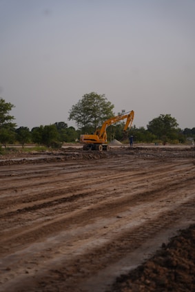 An excavator works on a construction site with a person.