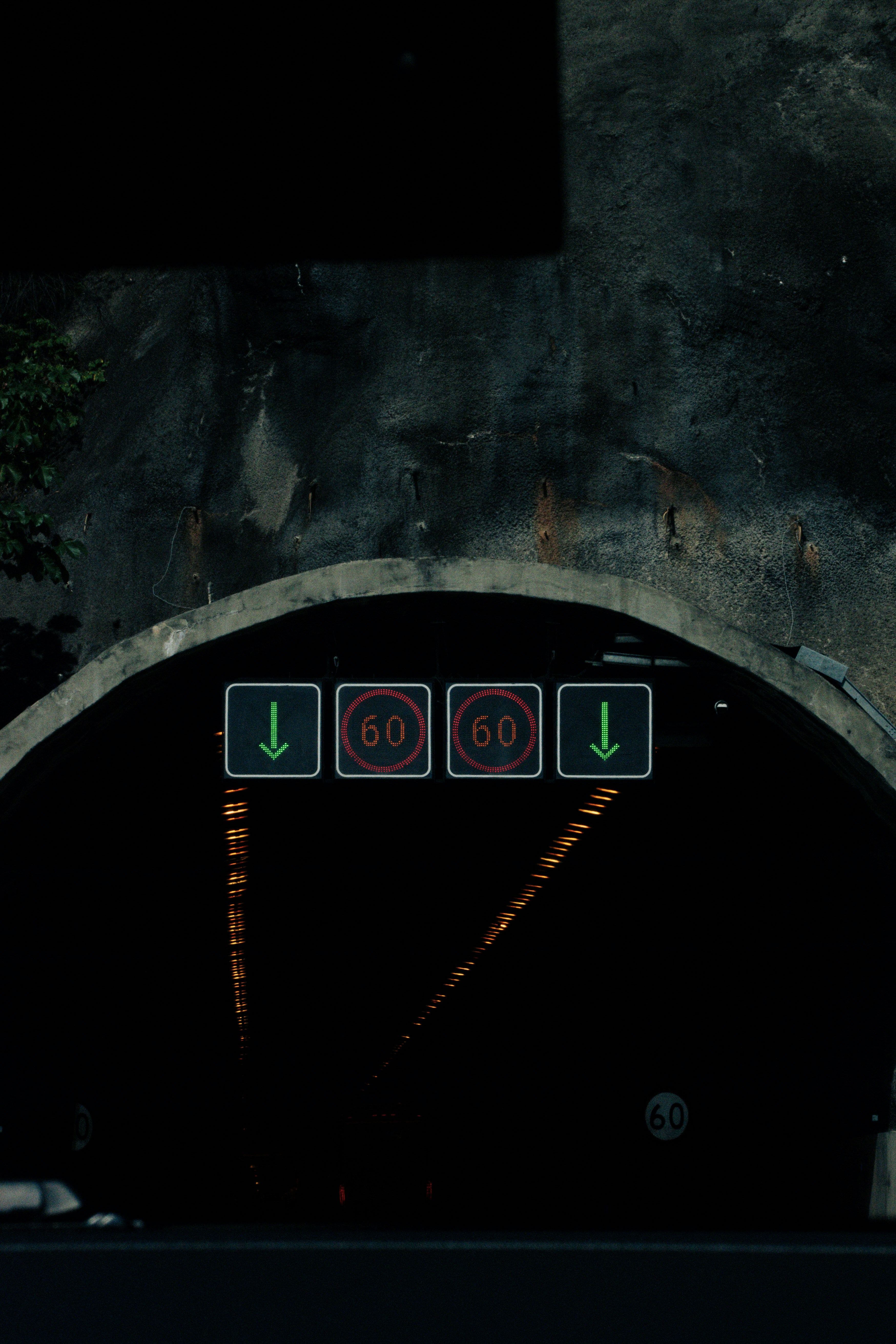 Tunnel entrance with speed limit signs and directional arrows.