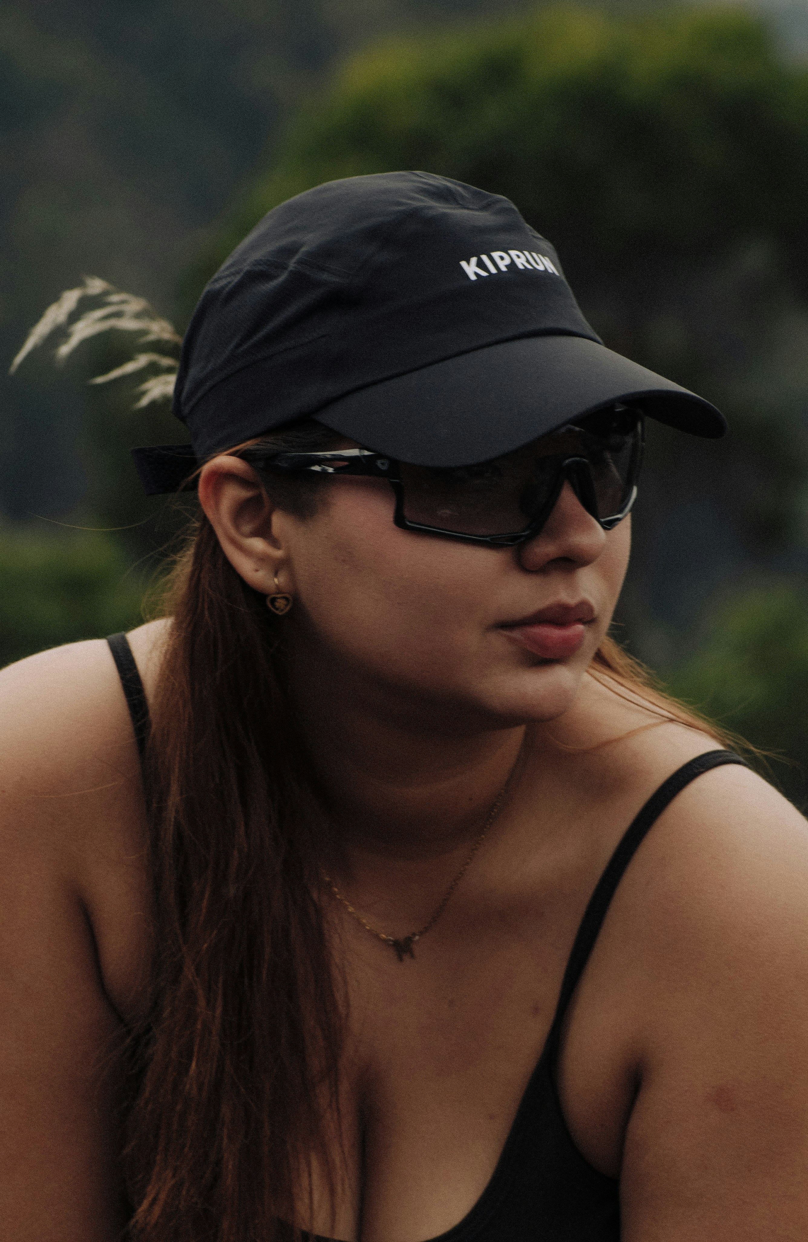 Woman wearing a black baseball cap and sunglasses outdoors sunglasses