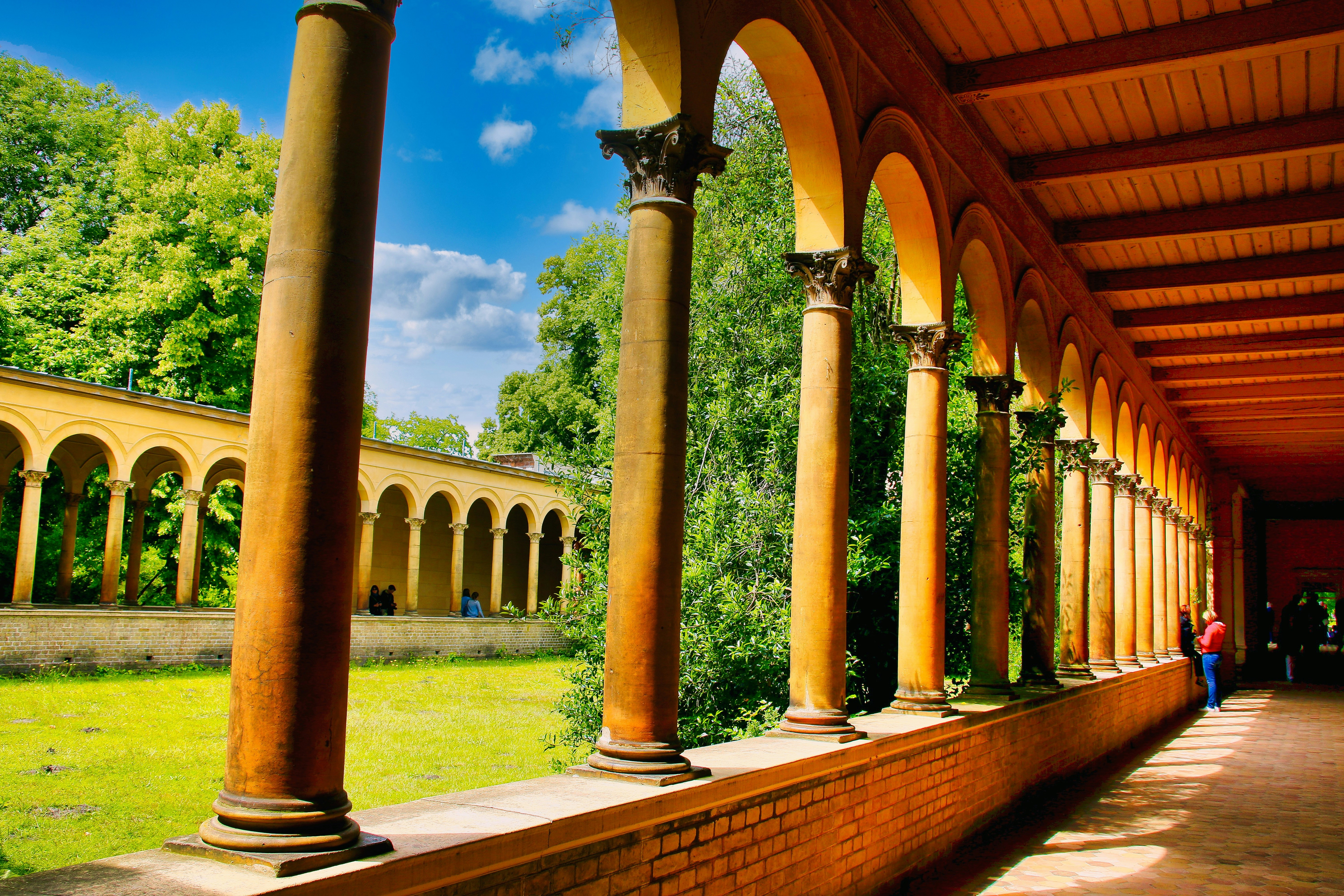 Arched colonnade with lush green trees and blue sky