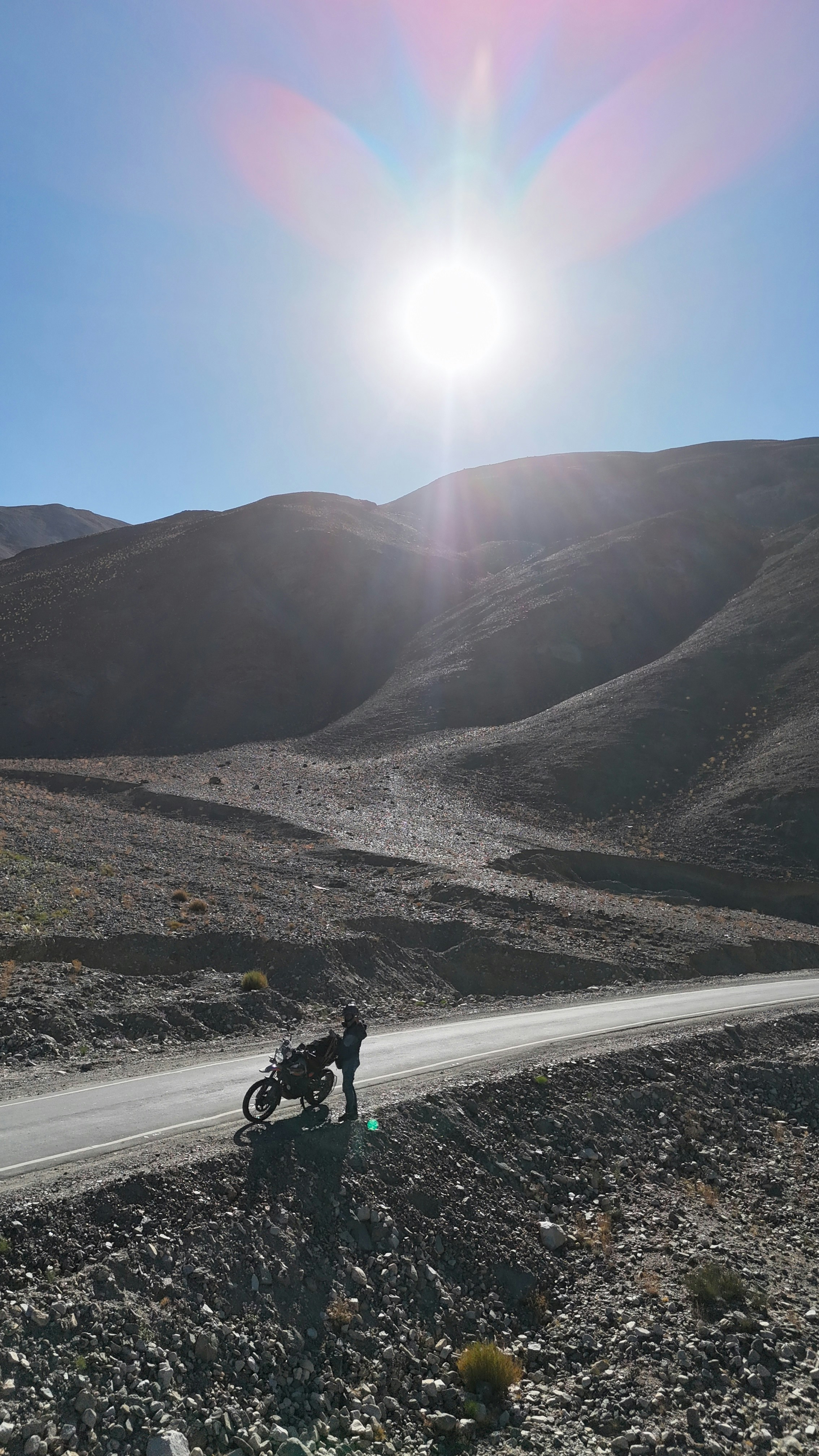 Una persona con una moto en una carretera con montañas.
